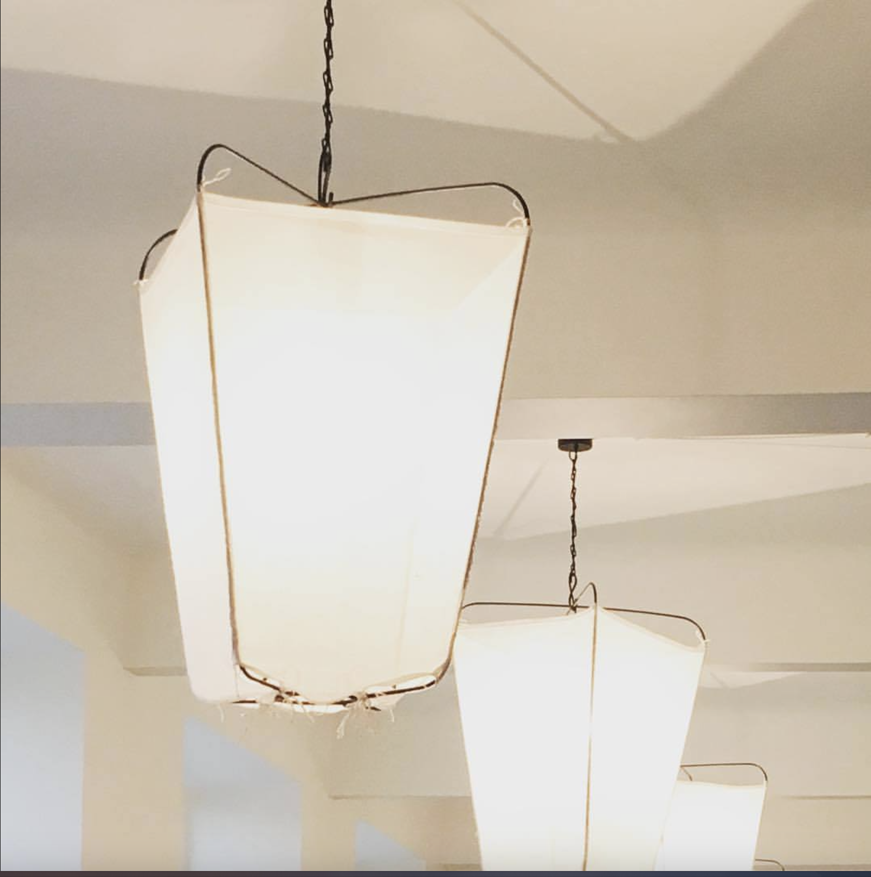 Two modern pendant light fixtures hanging from the ceiling with chain suspension, emitting bright light
www.gardenlampcollection.com