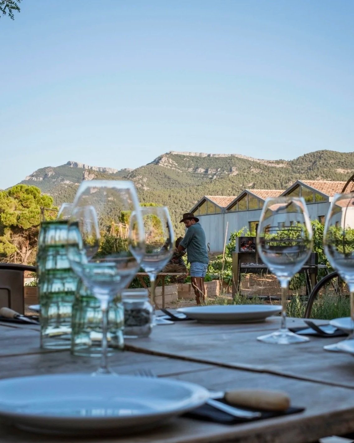 Personas reunidas alrededor de una parrilla en un espacio al aire libre, con botellas de champán en primer plano.