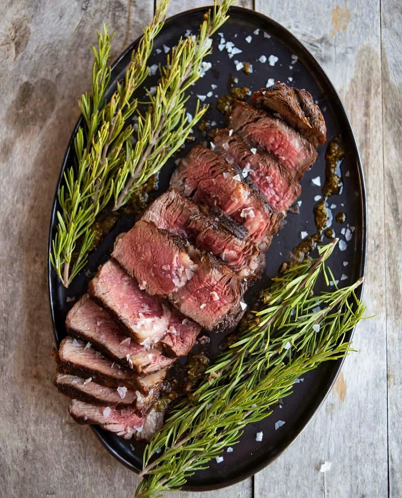 Personas reunidas alrededor de una parrilla en un espacio al aire libre, con botellas de champán en primer plano.
