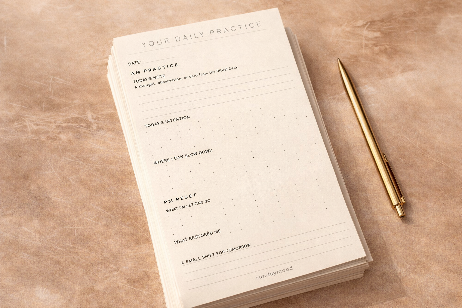 A daily practice journal page with sections for date, notes, intentions, and reflections, placed on a light brown surface with a gold pen beside it.