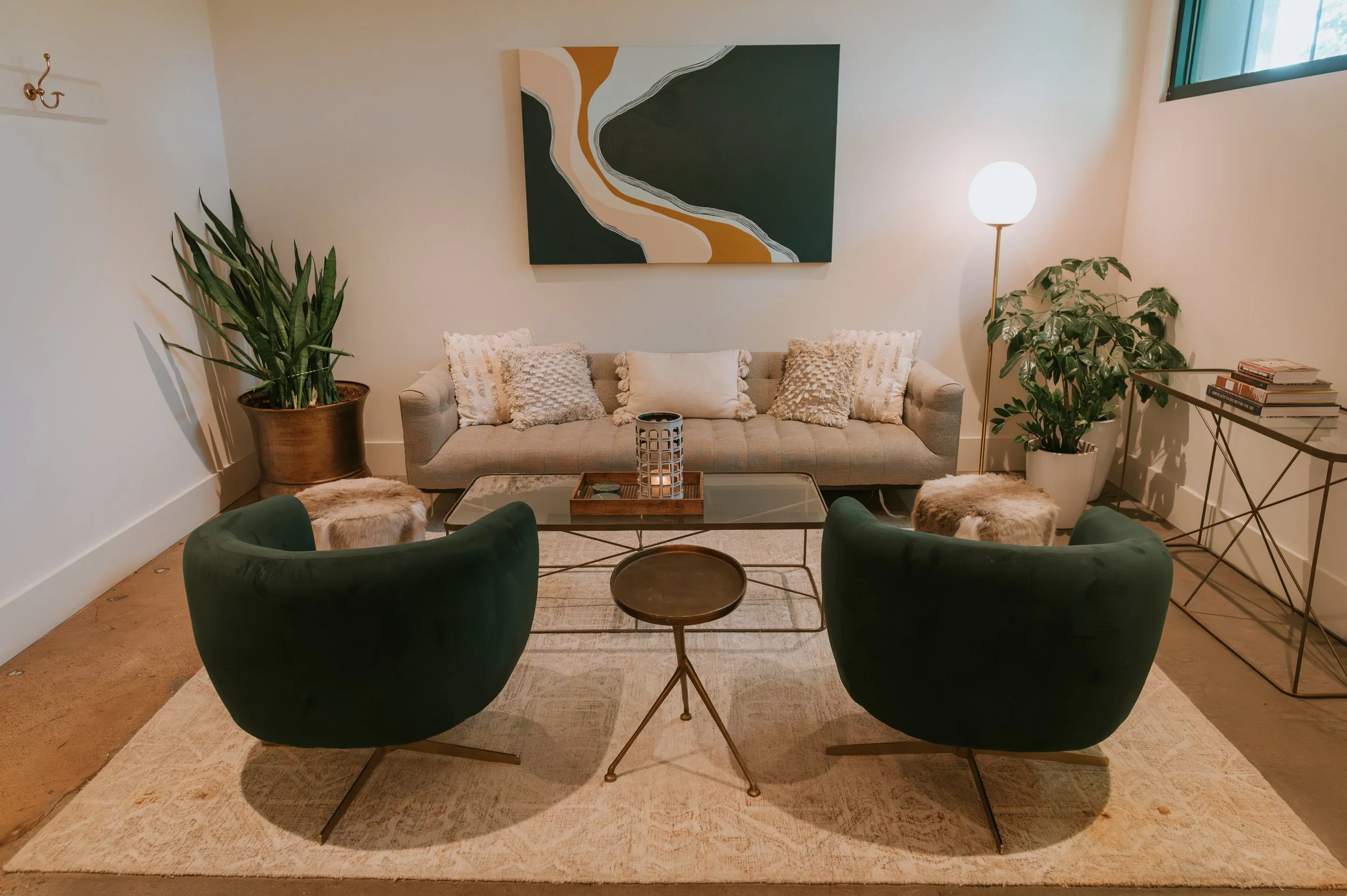 Bridal suite lounge with green velvet swivel chairs, a neutral sofa, abstract art and potted plants