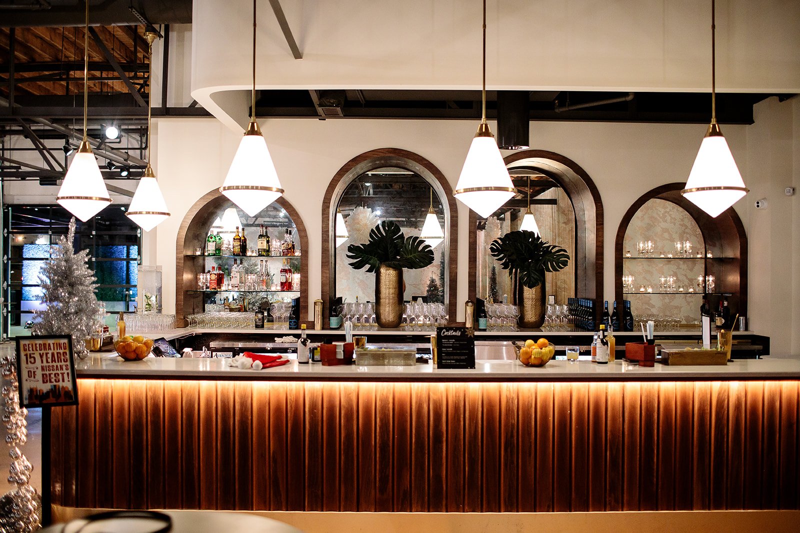 Saint Elle bar with arched mirrored shelving, globe pendant lights and a glowing wood-slat front