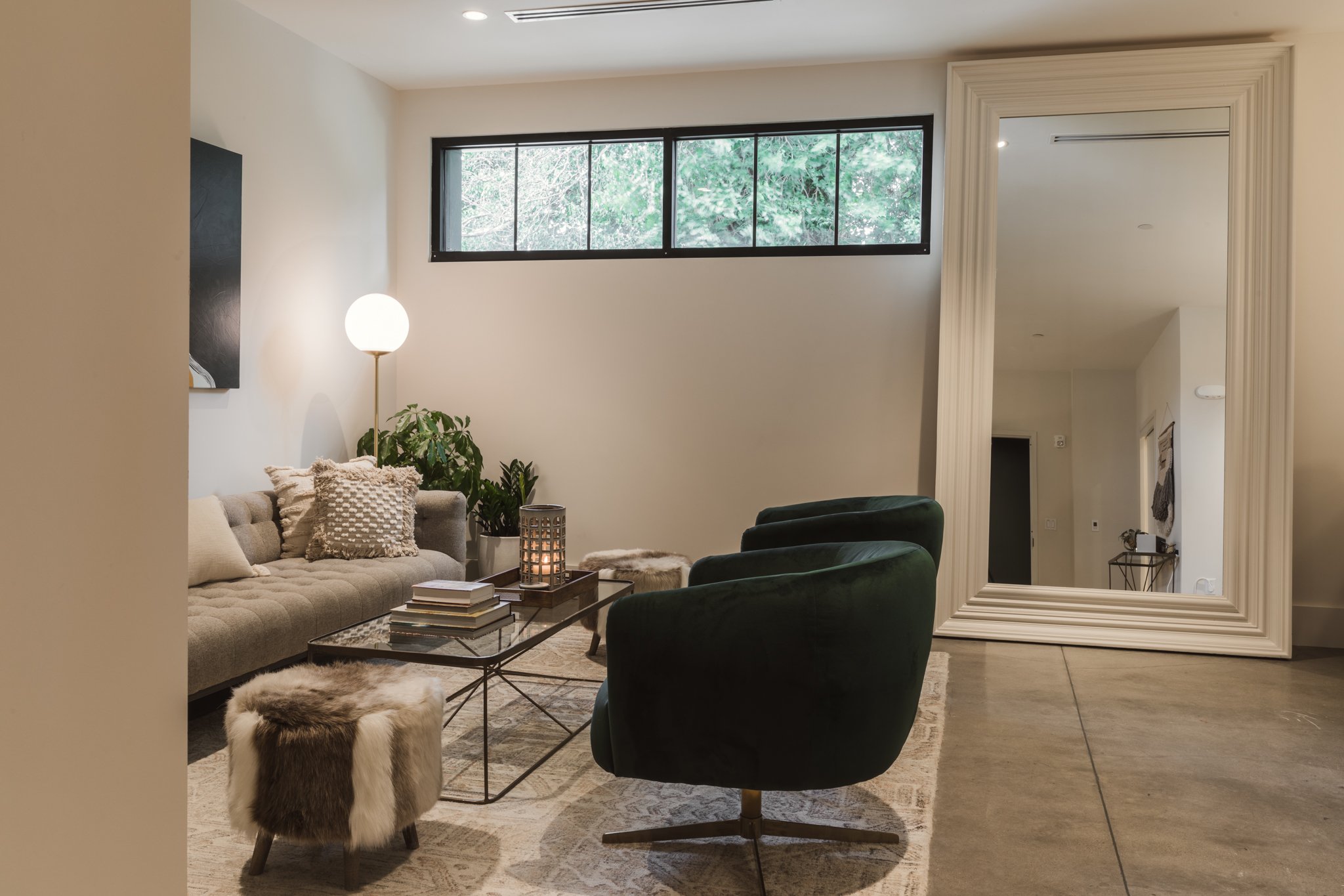The Suite's lounge with a full-length floor mirror, swivel chair, sofa and fur ottoman