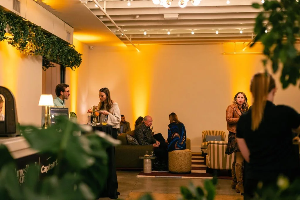 Guests relax on lounge furniture under warm amber uplighting beside the bar