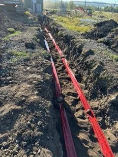Red fiber optic cables installed in an open trench