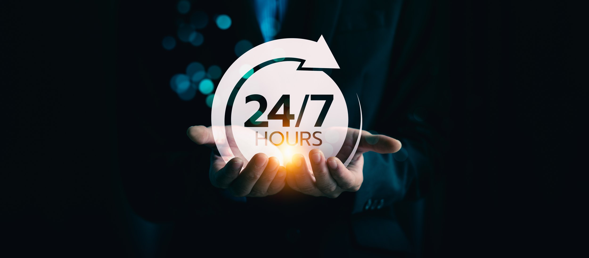 A person wearing a suit holding a glowing digital icon of a clock with an arrow circling around it, displaying '24/7 HOURS'.
