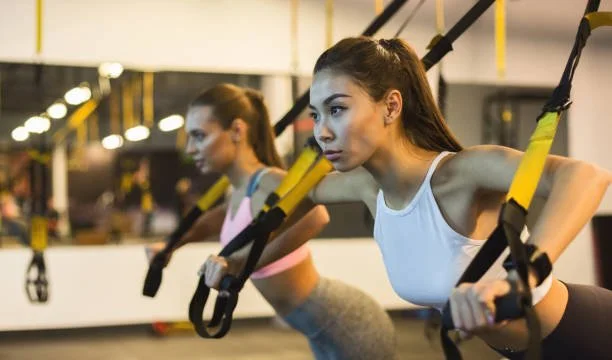 Two women doing TRX exercise