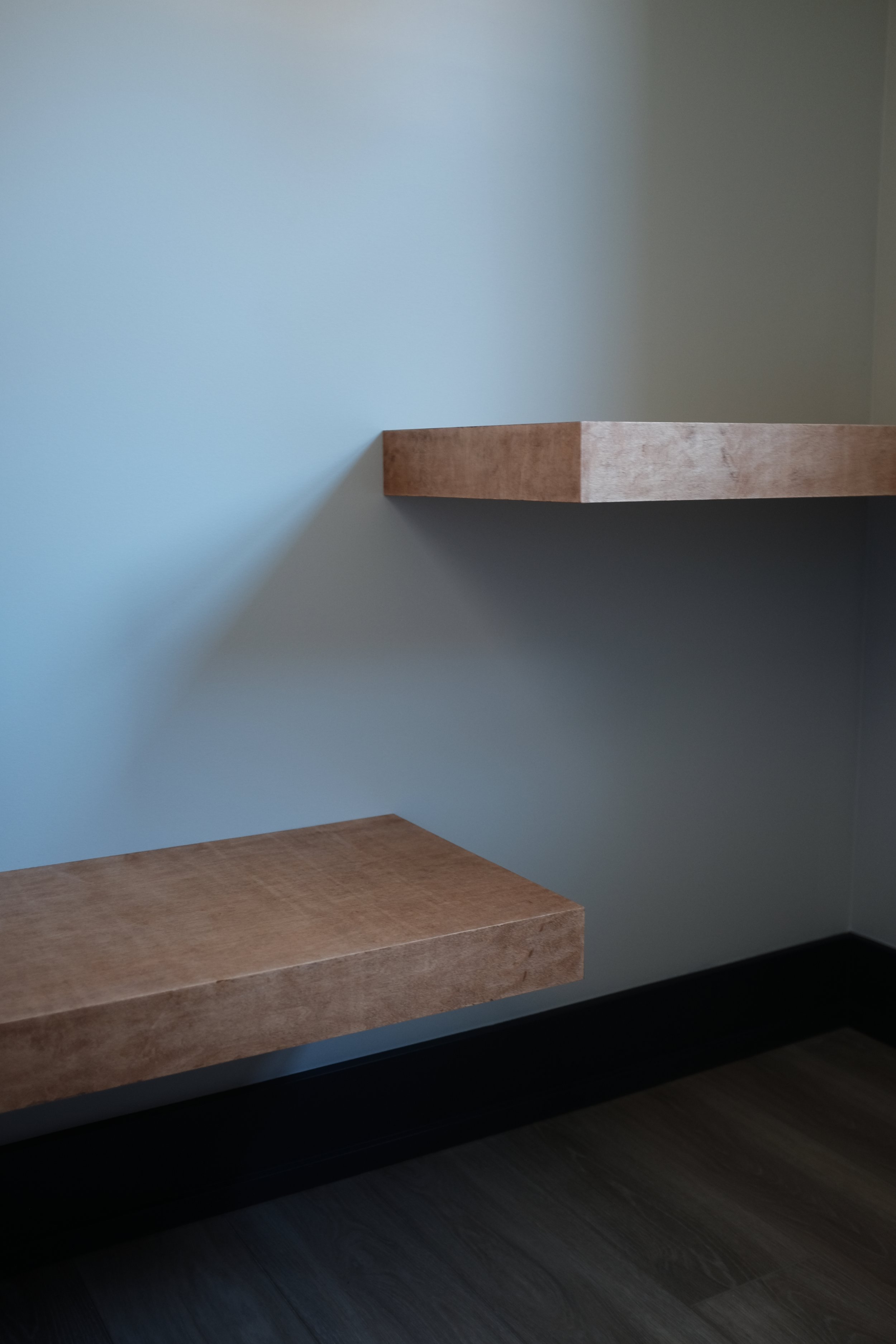 Two floating wooden shelves on a light blue wall