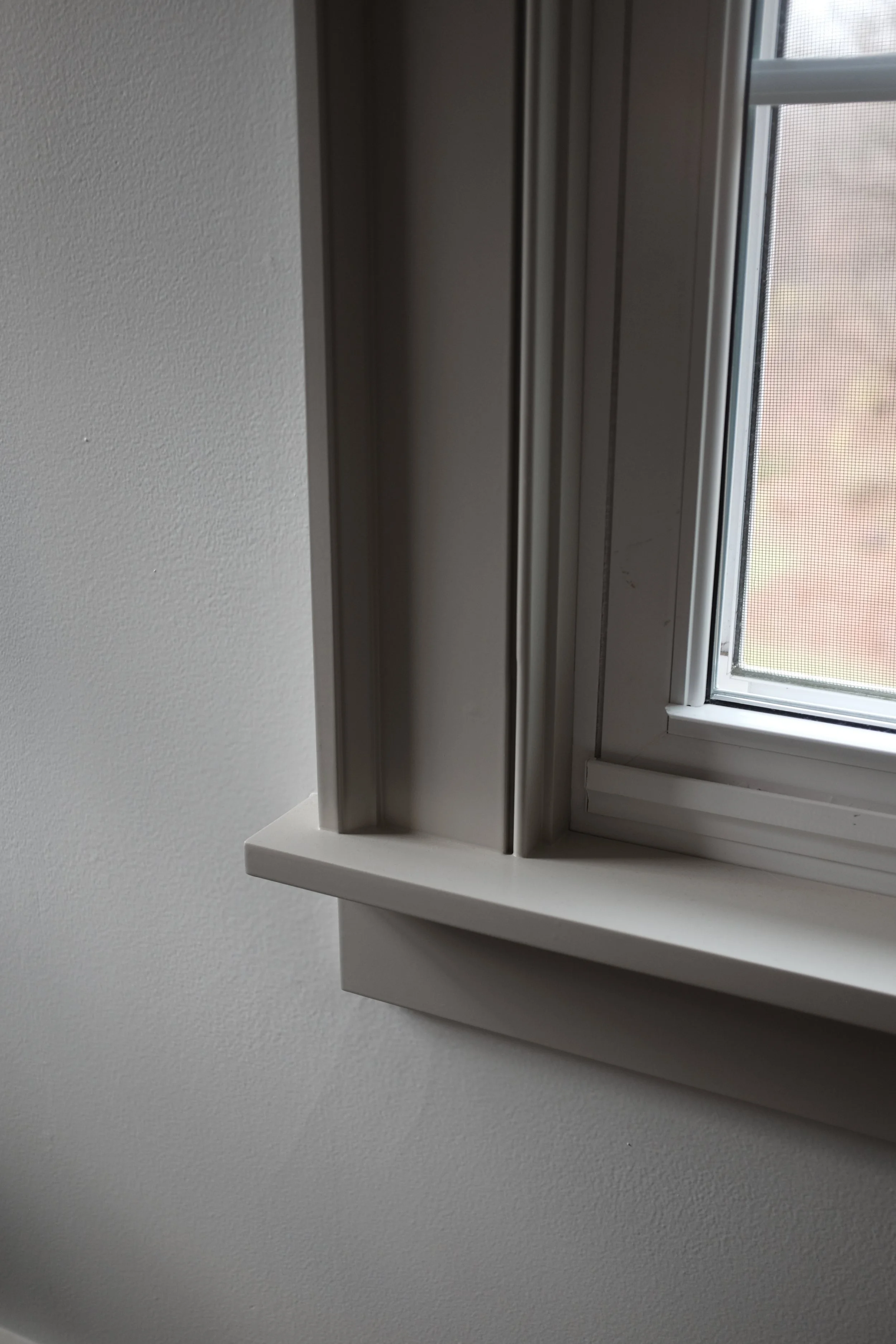 Interior view of a window frame with a white windowsill against a gray wall.