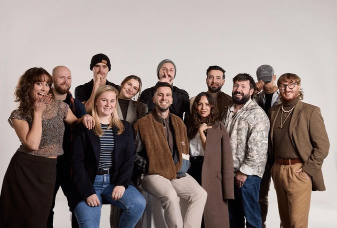 Group of ten diverse young adults standing and sitting together against a plain white background.
