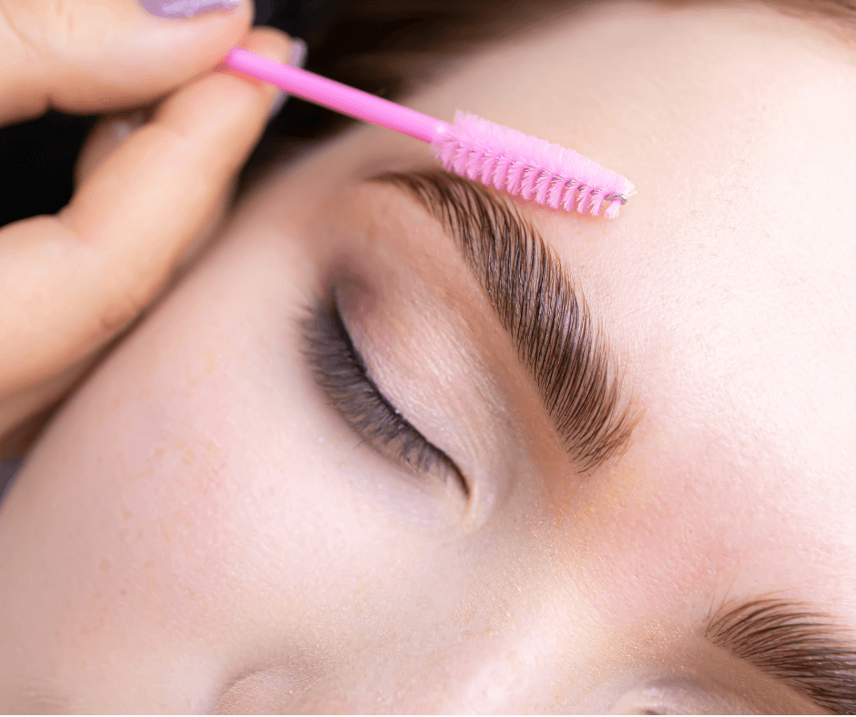 Person receiving eyebrow grooming using a pink spoolie brush.