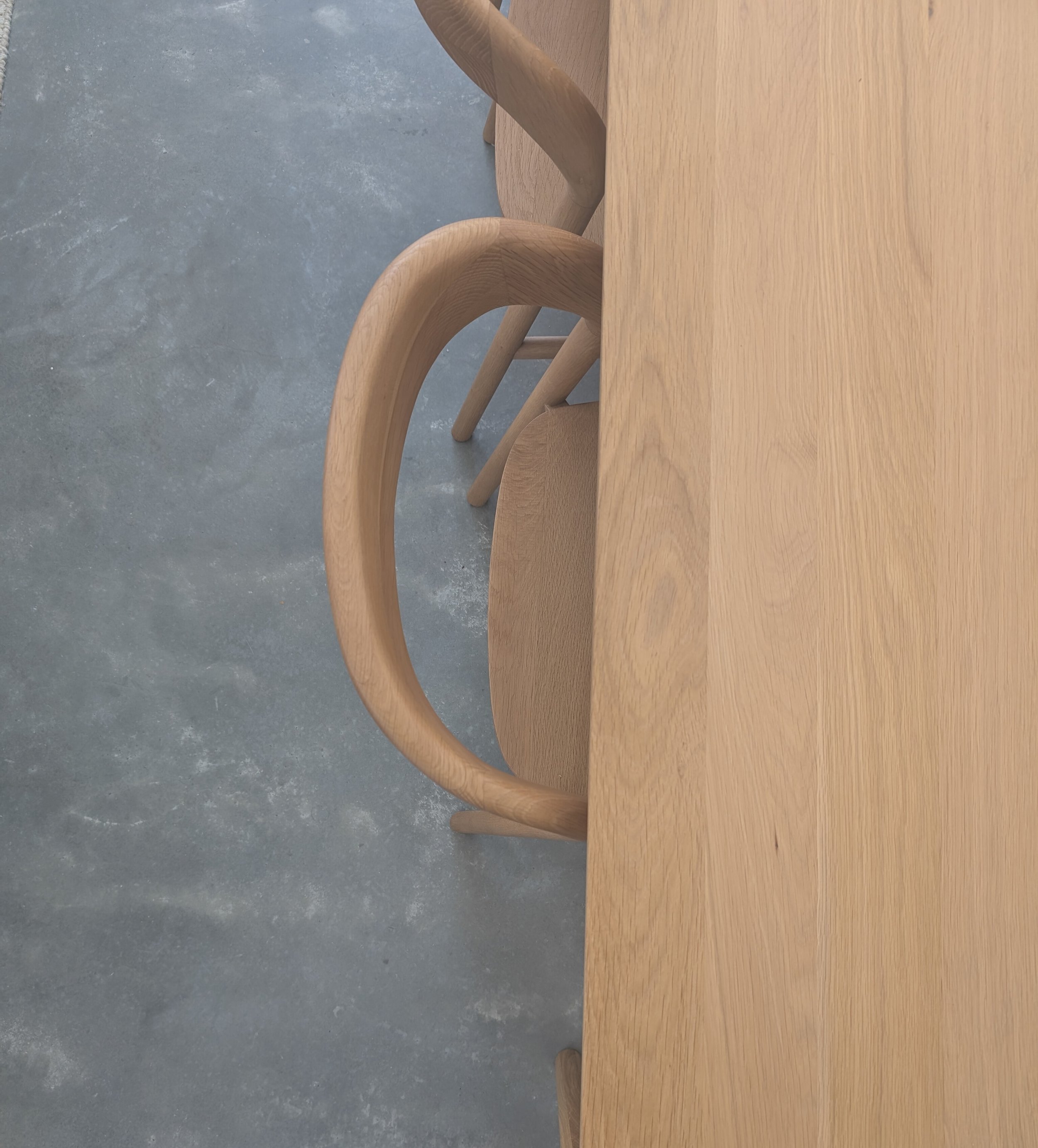 Wooden chairs around a wooden table on a concrete floor