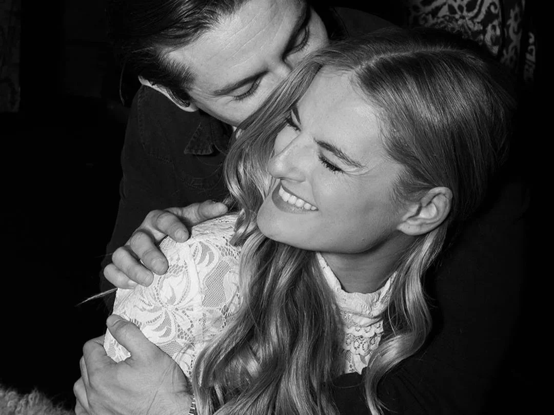 A man hugging a smiling woman with long hair, black and white photo.