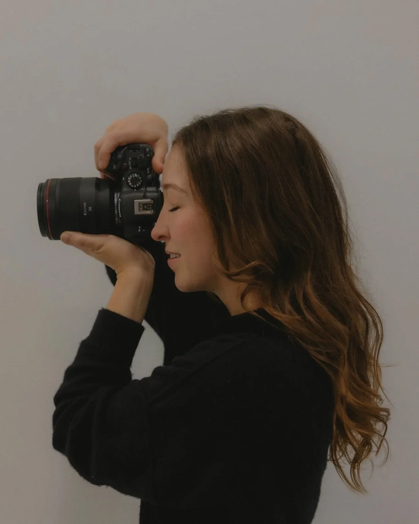 Portrait of Kirstin Mullins, a San Francisco wedding and elopement photographer, holding her camera in a studio setting.