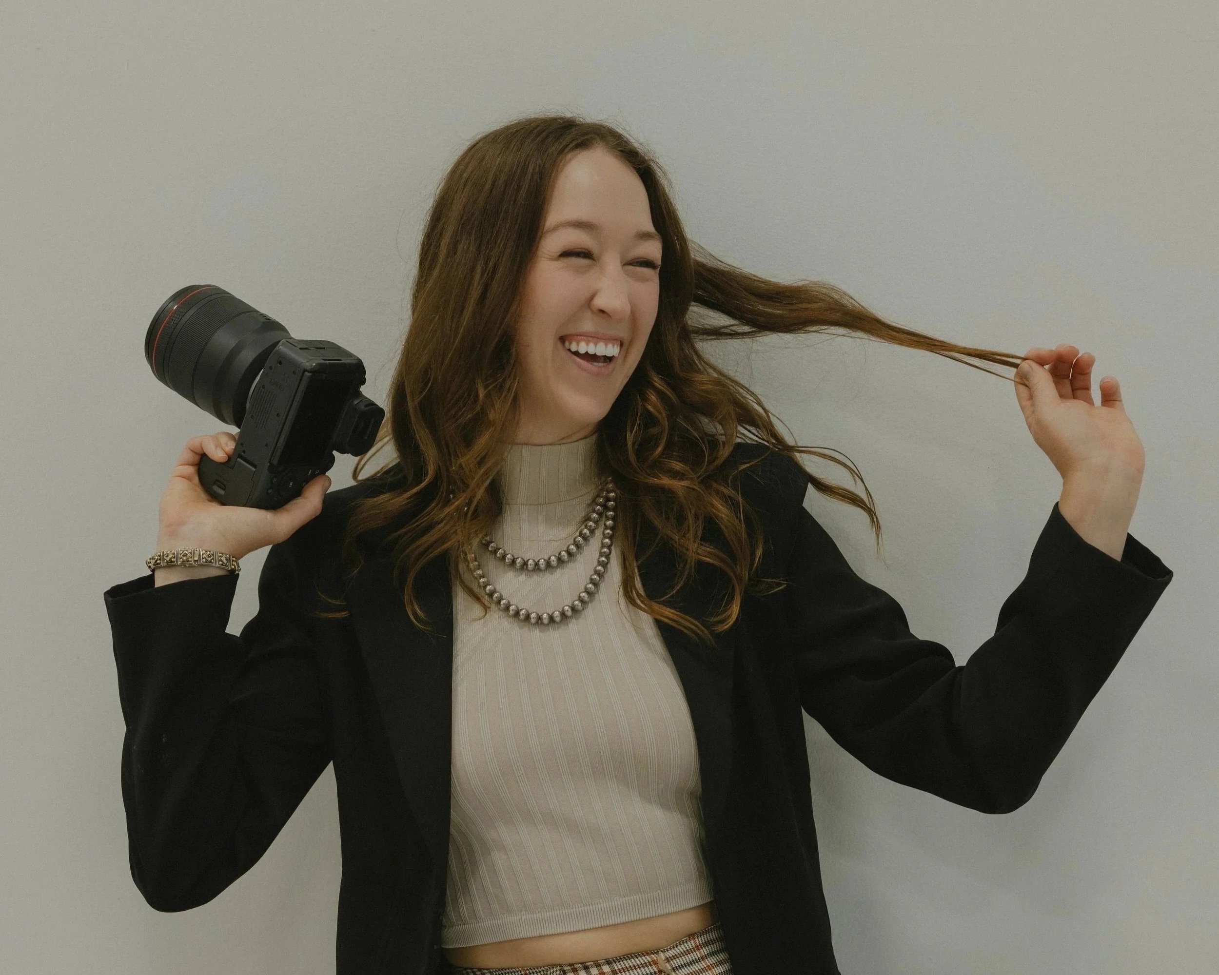 Portrait of San Francisco wedding and elopement photographer Kirstin Mullins laughing and holding her camera in a candid documentary-style photo.