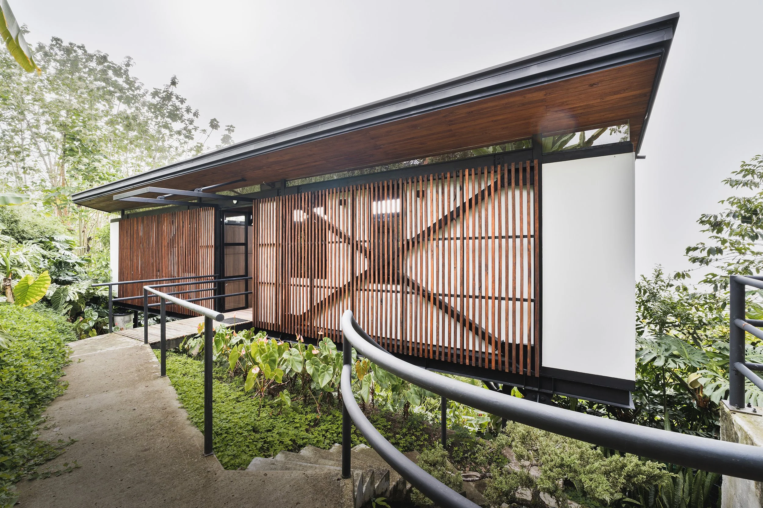 Foto de casa moderna con listones de madera en fachada, rodeada de vegetación