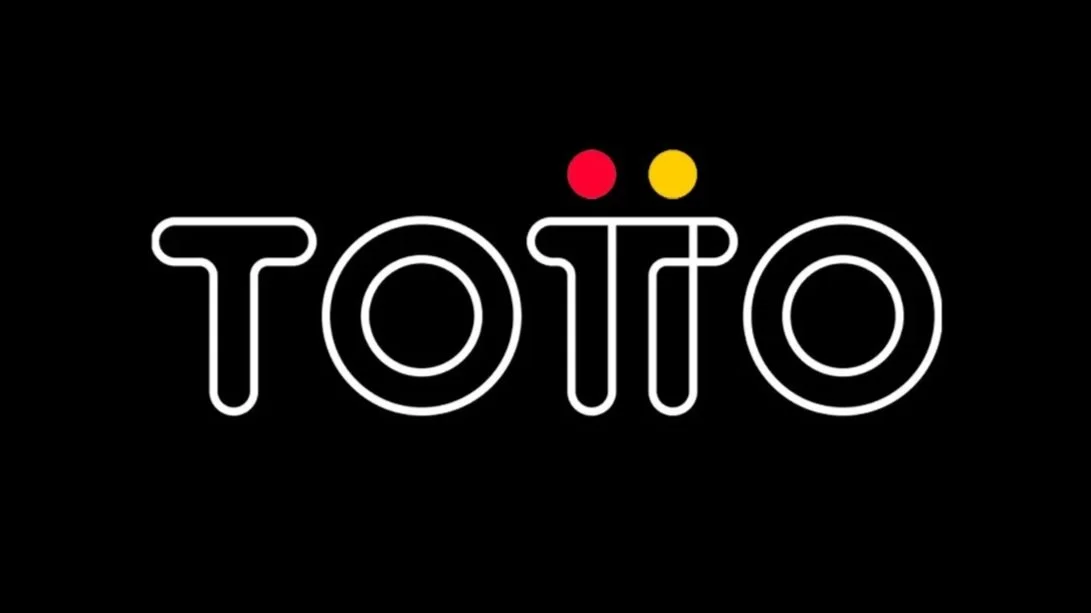 Neon sign spelling 'TOITO' in white letters on black background with two small circles, one red and one yellow, above the second 'I'.