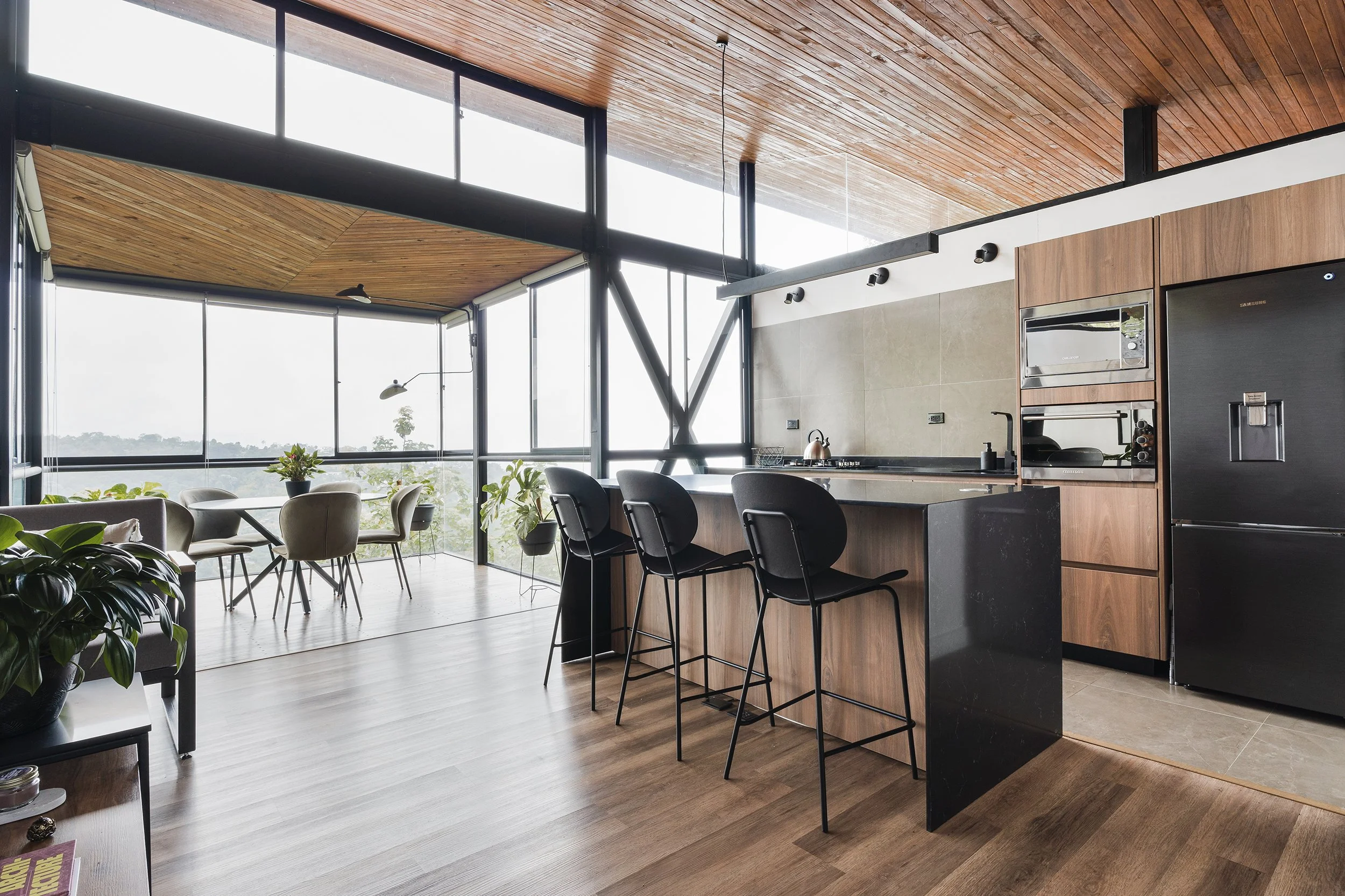 Fotografía de diseño de interiores, de una cocina moderna, con el comedor de fondo y grandes ventanales