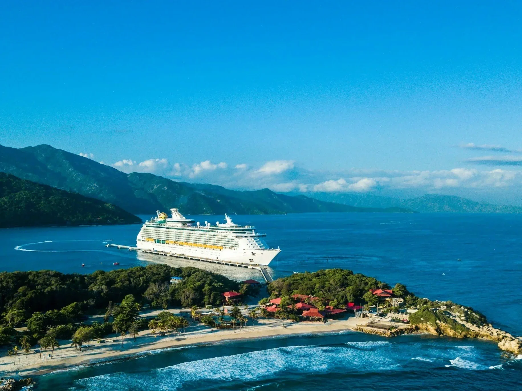 City skyline with tall skyscrapers, including a building with tinted glass, framed by palm trees and trees in the foreground, with people visible at the bottom.