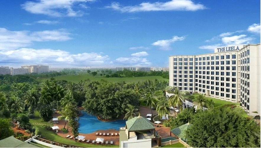 The Leela Mumbai tower above lush gardens and pool