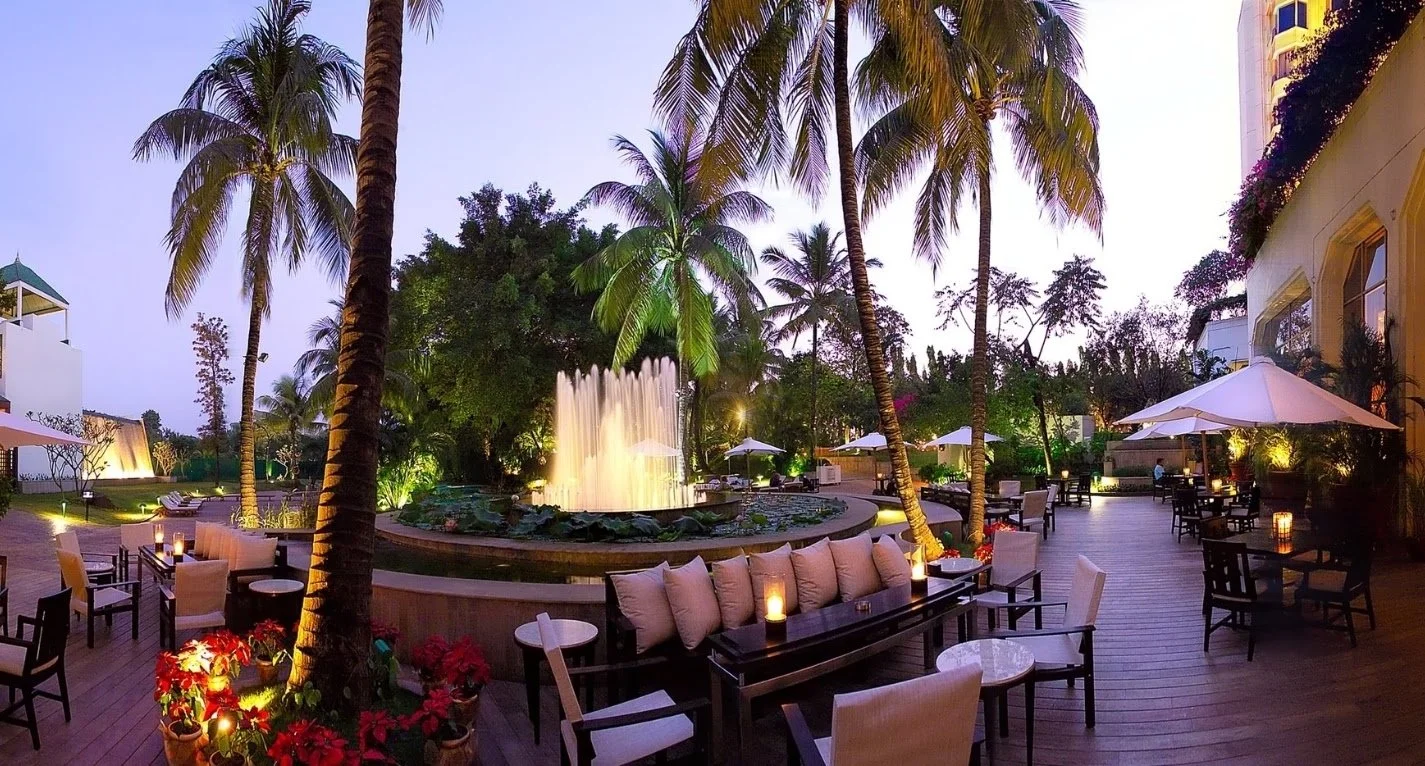 Poolside garden with fountain at dusk at The Leela Mumbai