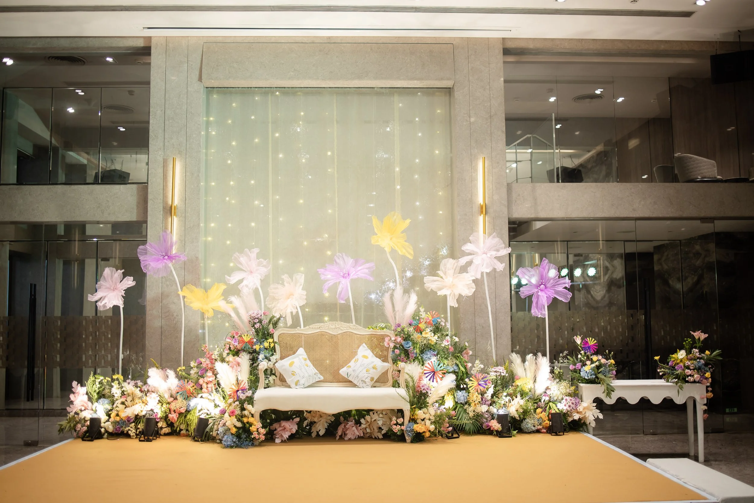 Pastel floral stage with a white sofa at Blue Sea Banquets