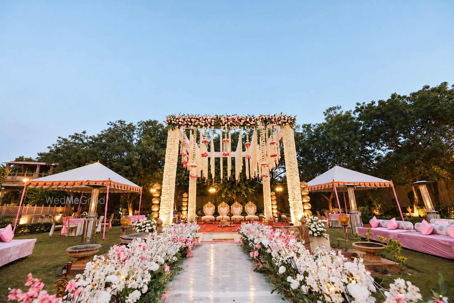 Dusk wedding mandap with flower-lined aisle.png
