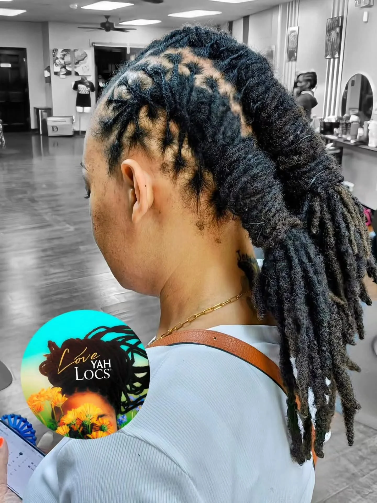 A woman with styled dreadlocks, partially black and blond, in a salon setting.