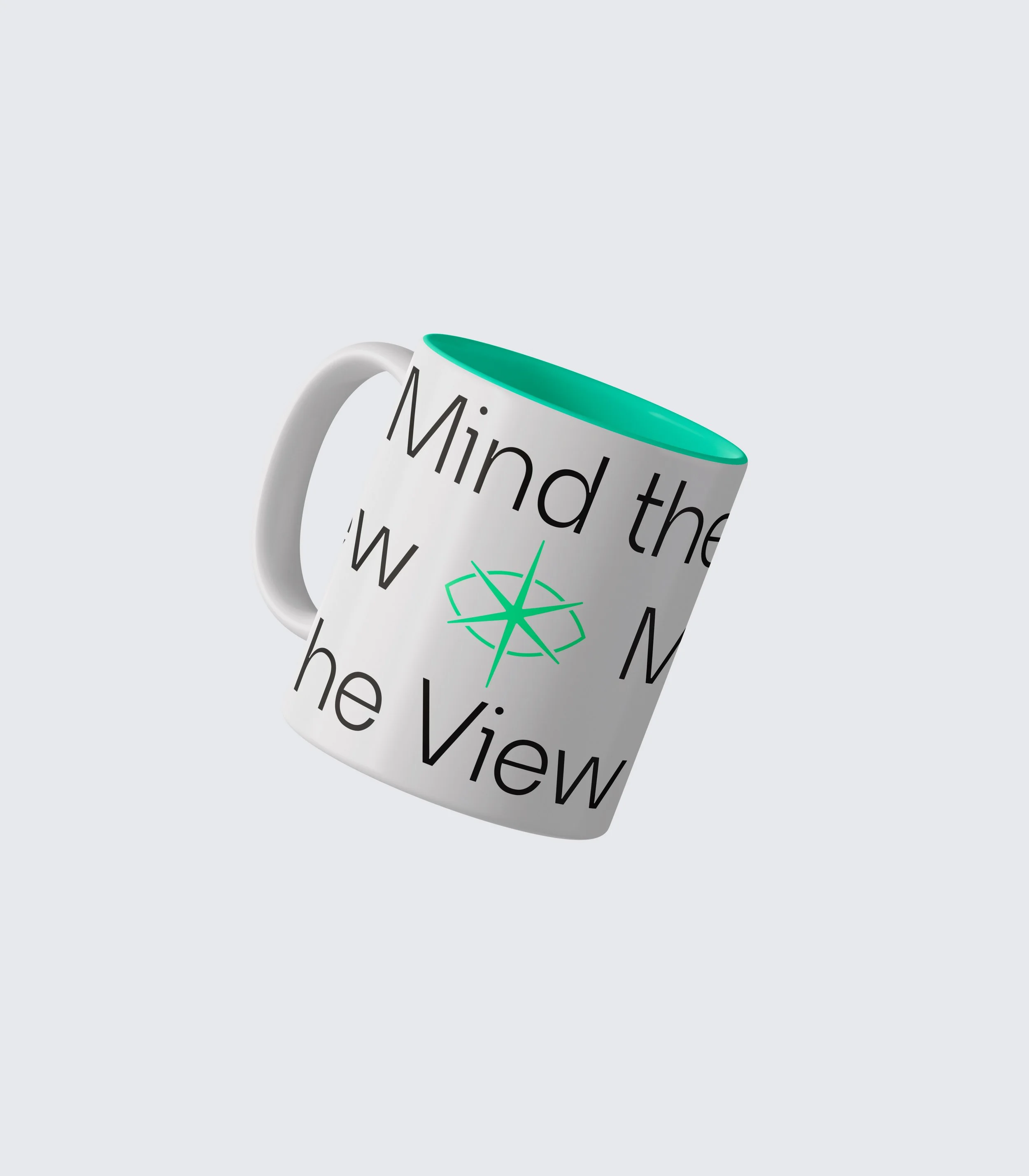 Witte beker met groene binnenkant en tekst 'Mind the View' en een groen kompas symbool, ligt schuin op een lichte achtergrond.