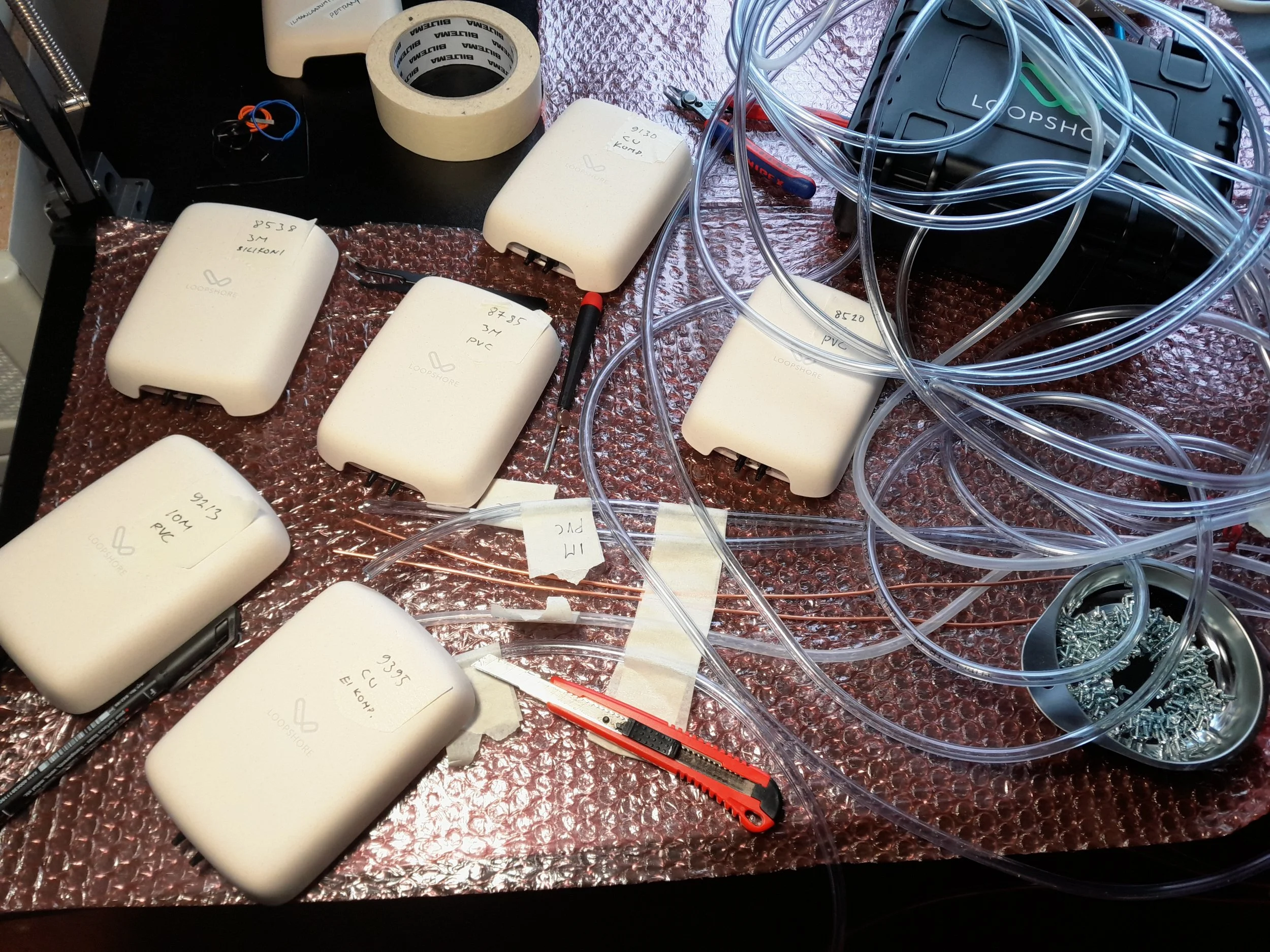 Kuusi Loop Deltaa, letkut merkitty ja valmiina kytkettäväksi. Etualalla kupariputket, oikealla PVC-letkukerät.