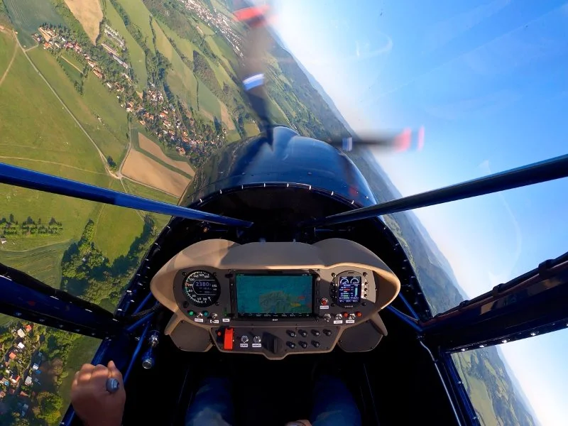 Cockpit of a small aircraft with multiple digital screens displaying navigation, altitude, and engine information.