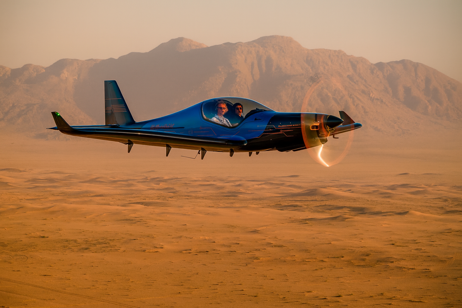 A small jet aircraft with a sleek black, blue, and orange design taxis on the runway, with pilots inside wearing sunglasses and communication headsets.