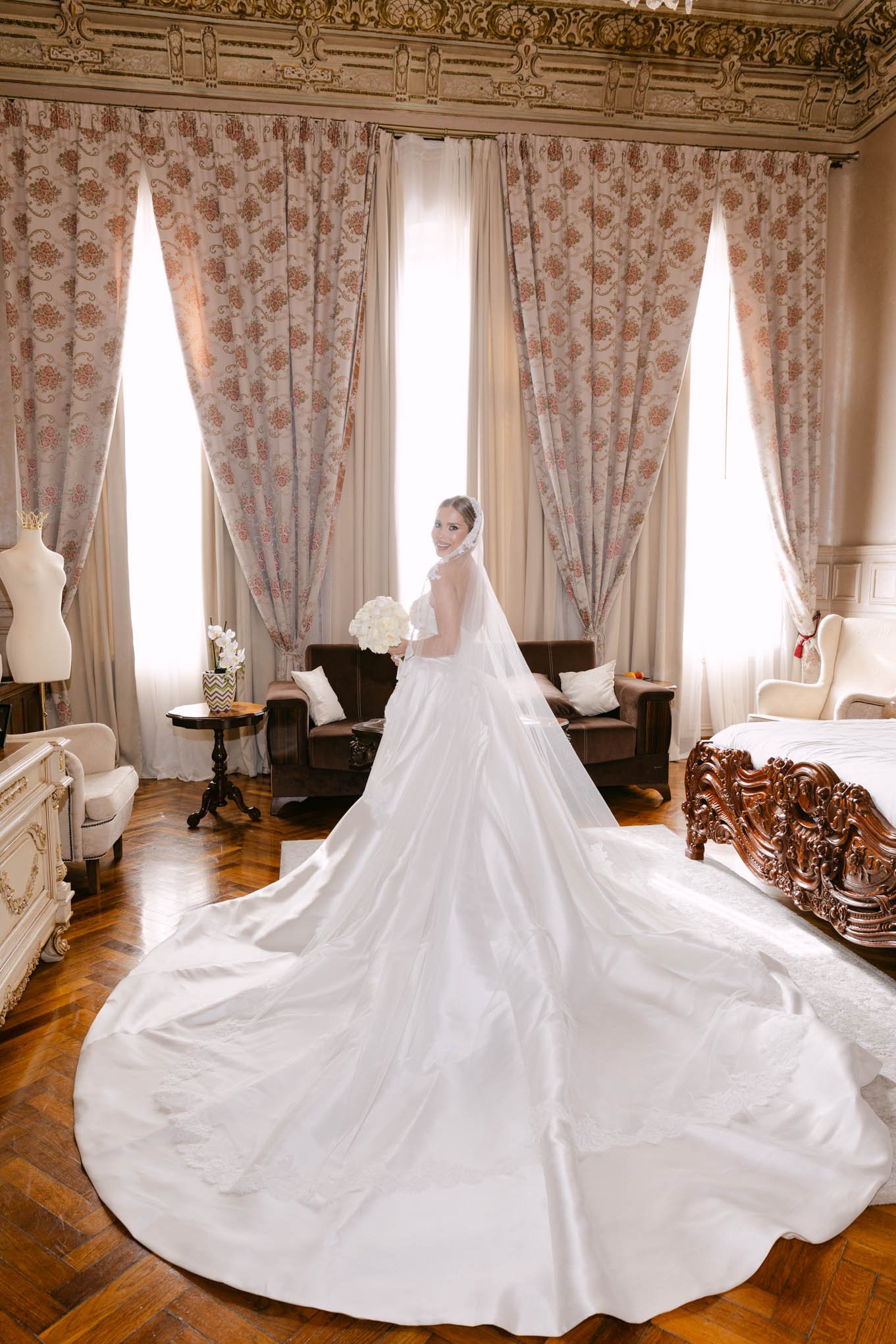 Bride in a wedding dress holding a bouquet in a decorated room with large windows and patterned curtains. italian style wedding, as seen in vogue!