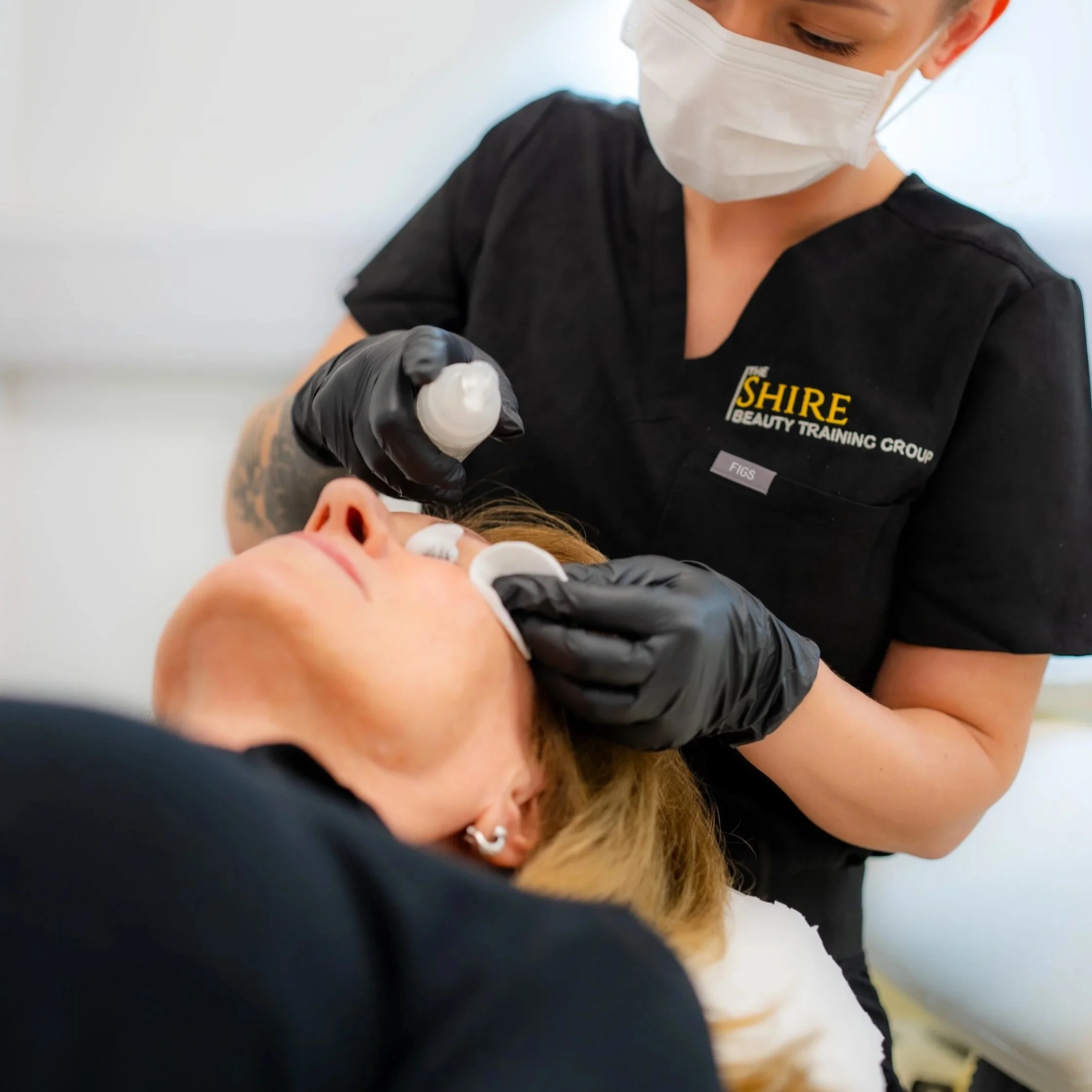Eyelash extension application with a pink protective paper underneath the eyelid.