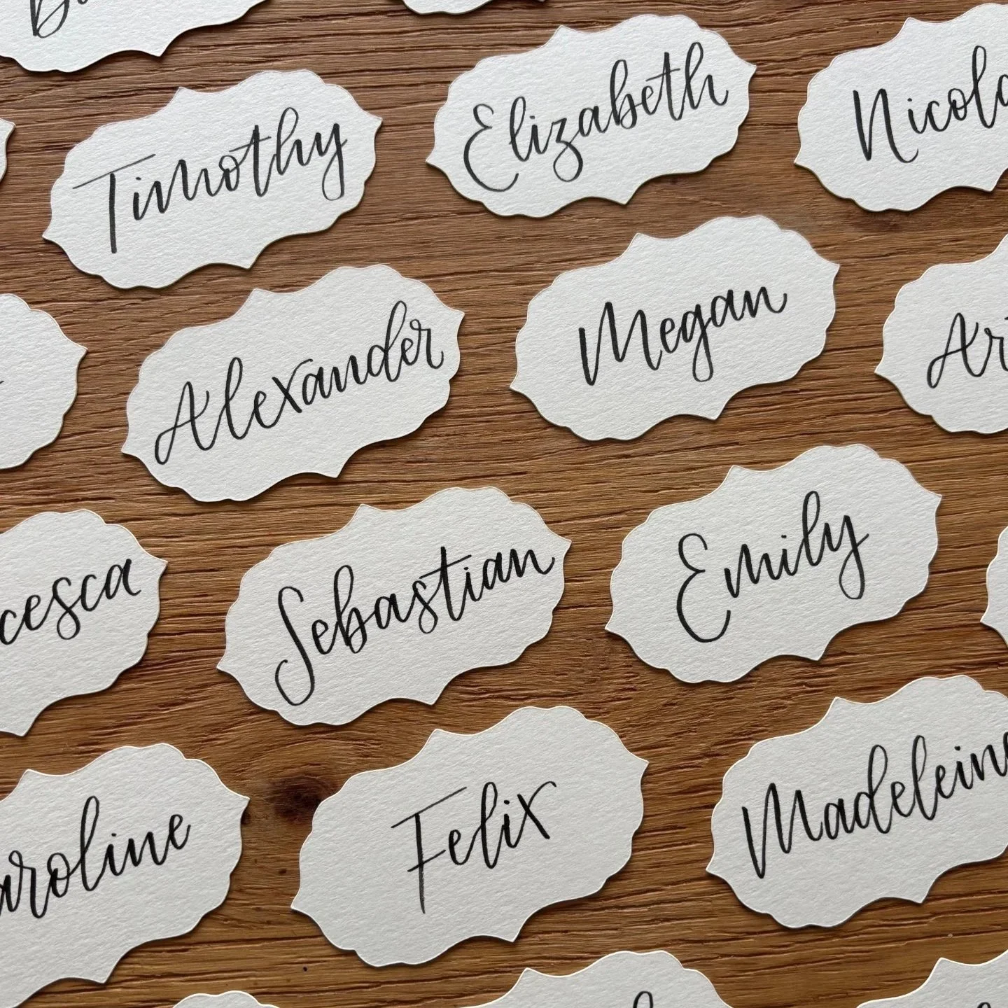 Several fancy edged place name flat layer onto a wooden table, hand lettered with modern calligraphy