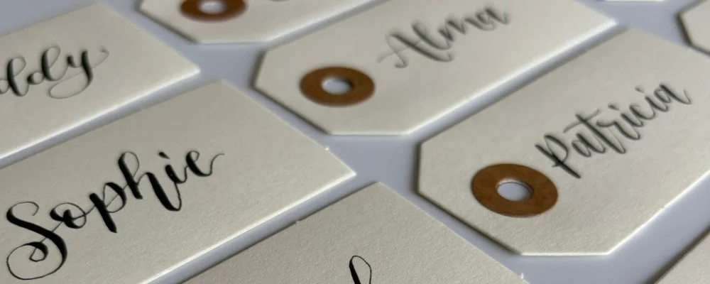 Hand lettered place names, created on small cream luggage labels, with names written in modern calligraphy