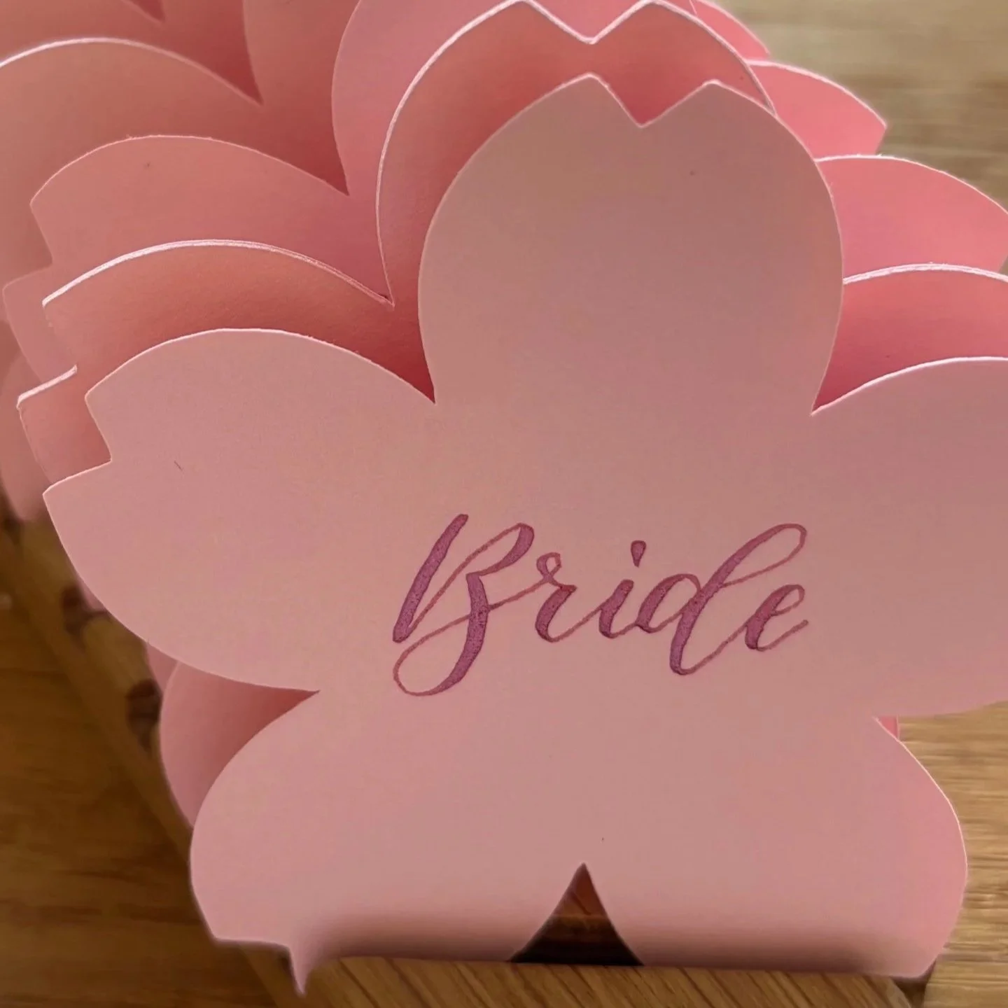 Blossom shaped name place, pale pink, lettered in modern calligraphy with metallic pink
