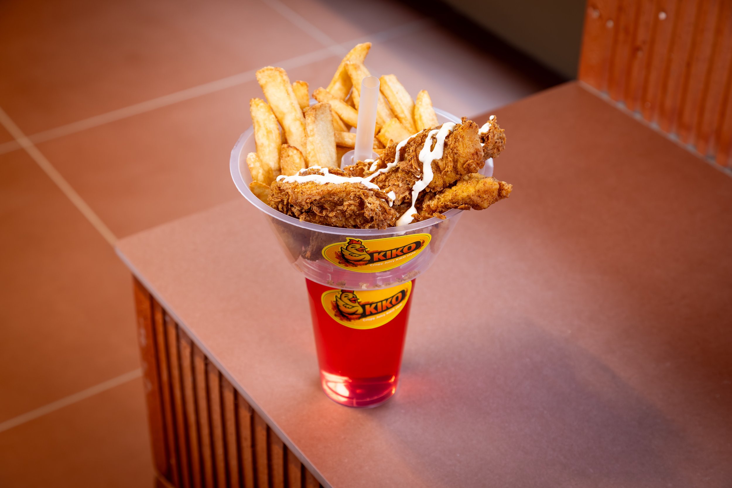 Kjemisk frites, kylling og saus i en rød KIKO-kopp.