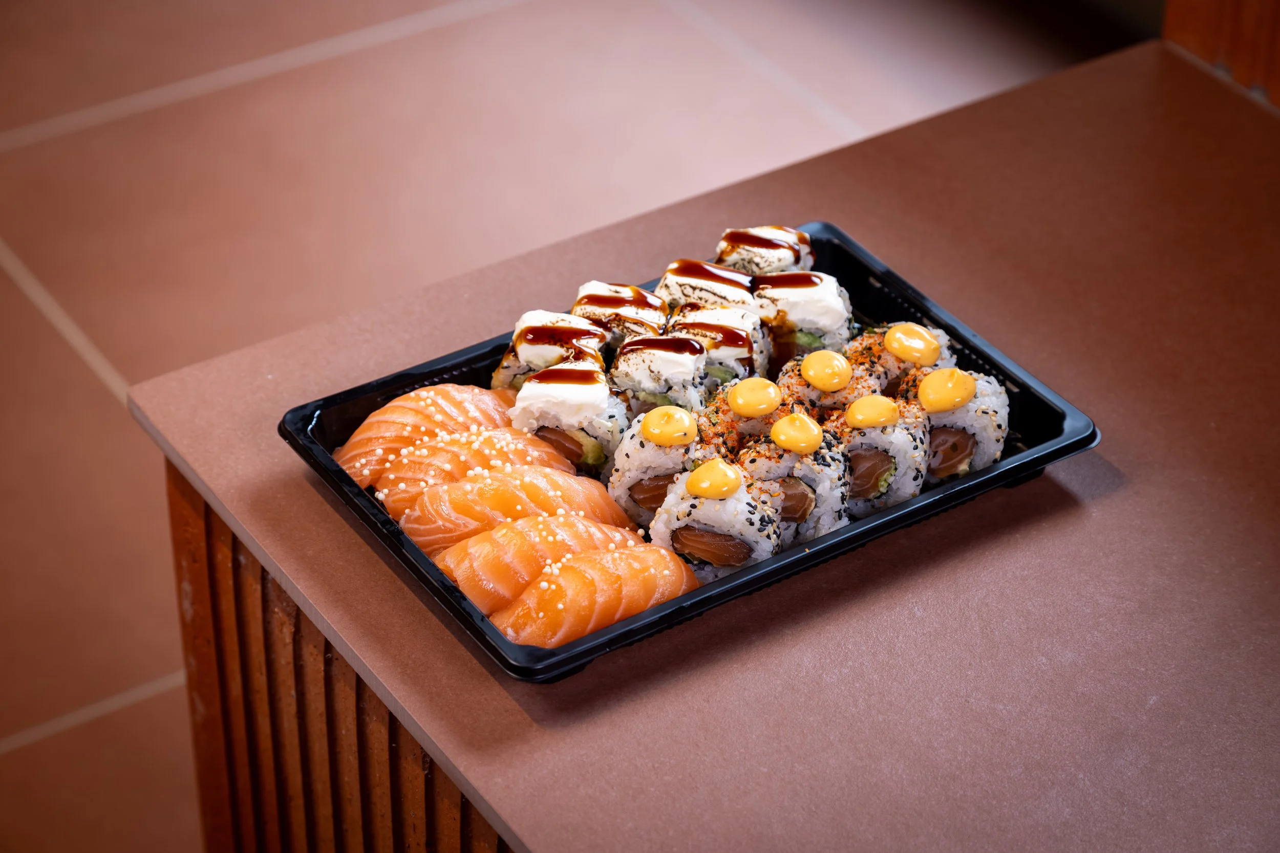 Sushi på en svart tallerken med ulike typer, inkludert laks, maki og sashimi.