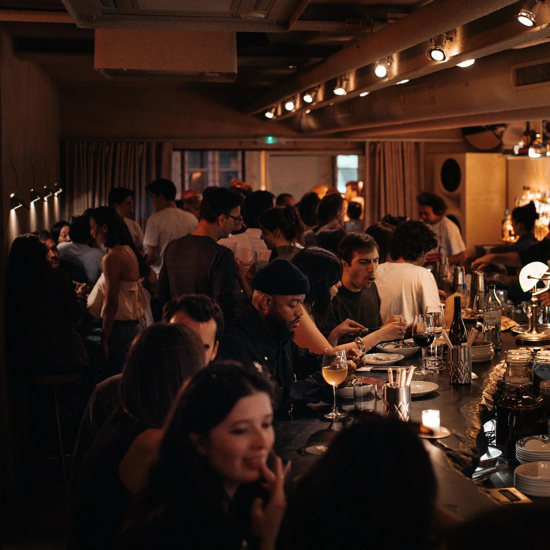 Interior of a busy and crowded cocktail bar with people listening to music and drinking cocktails while having dinner