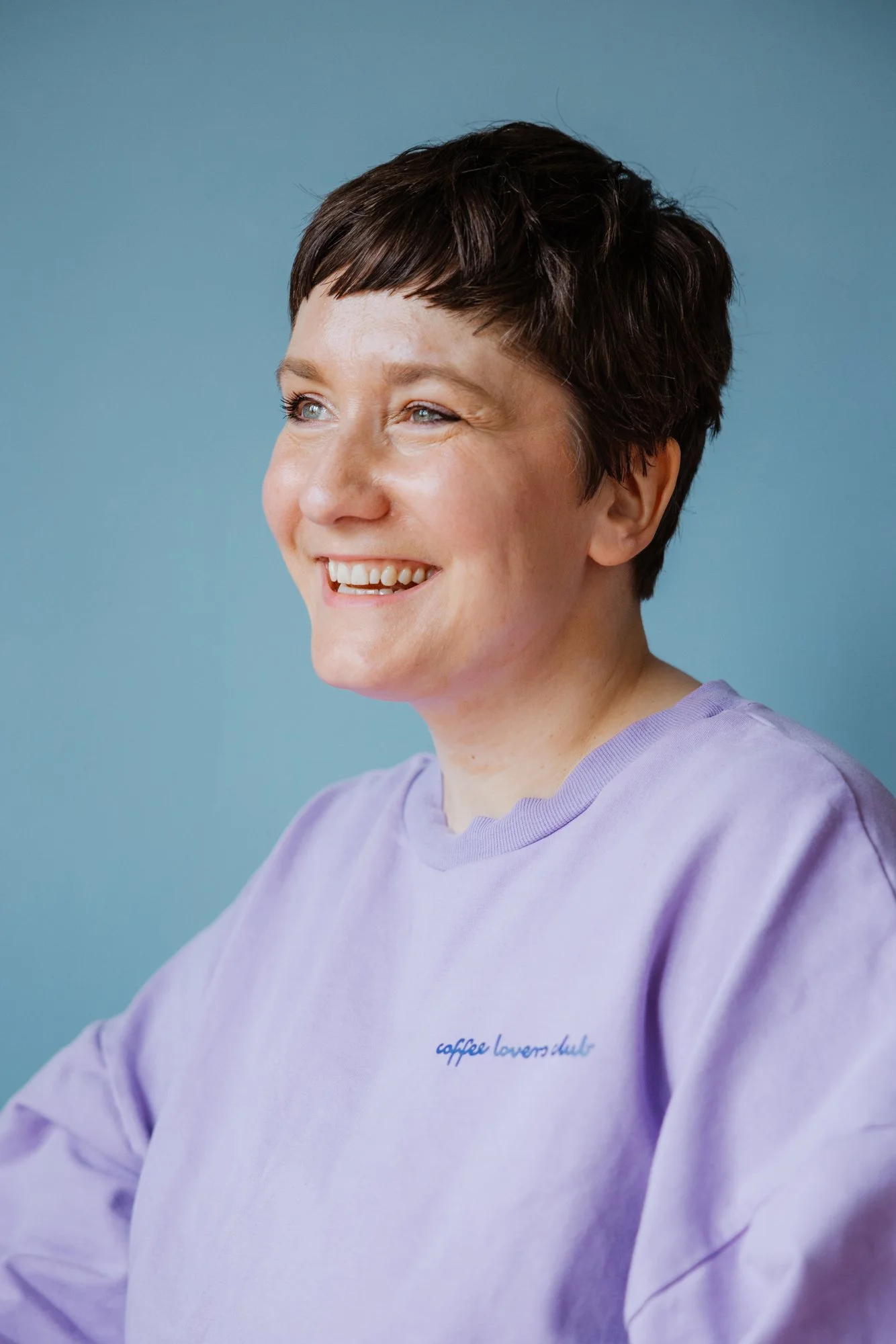 Autorin Elisabeth Rank in lila Pulli vor blauem Hintergrund