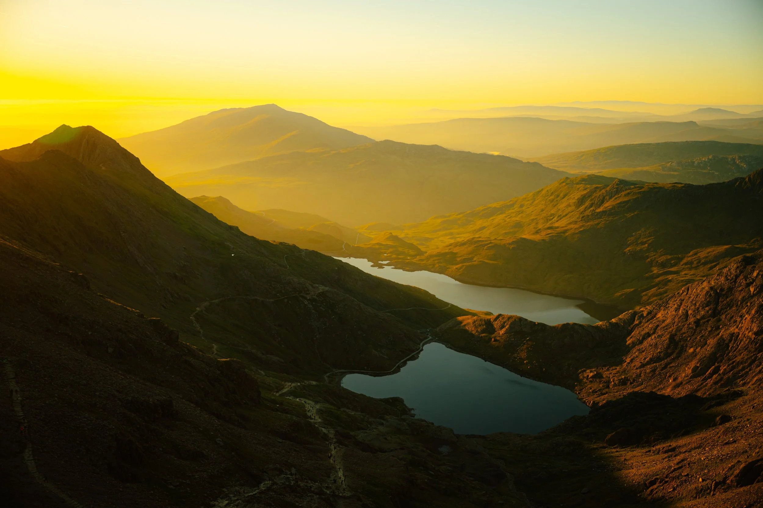 Sunrise over a mountainous landscape with two lakes in the valley.