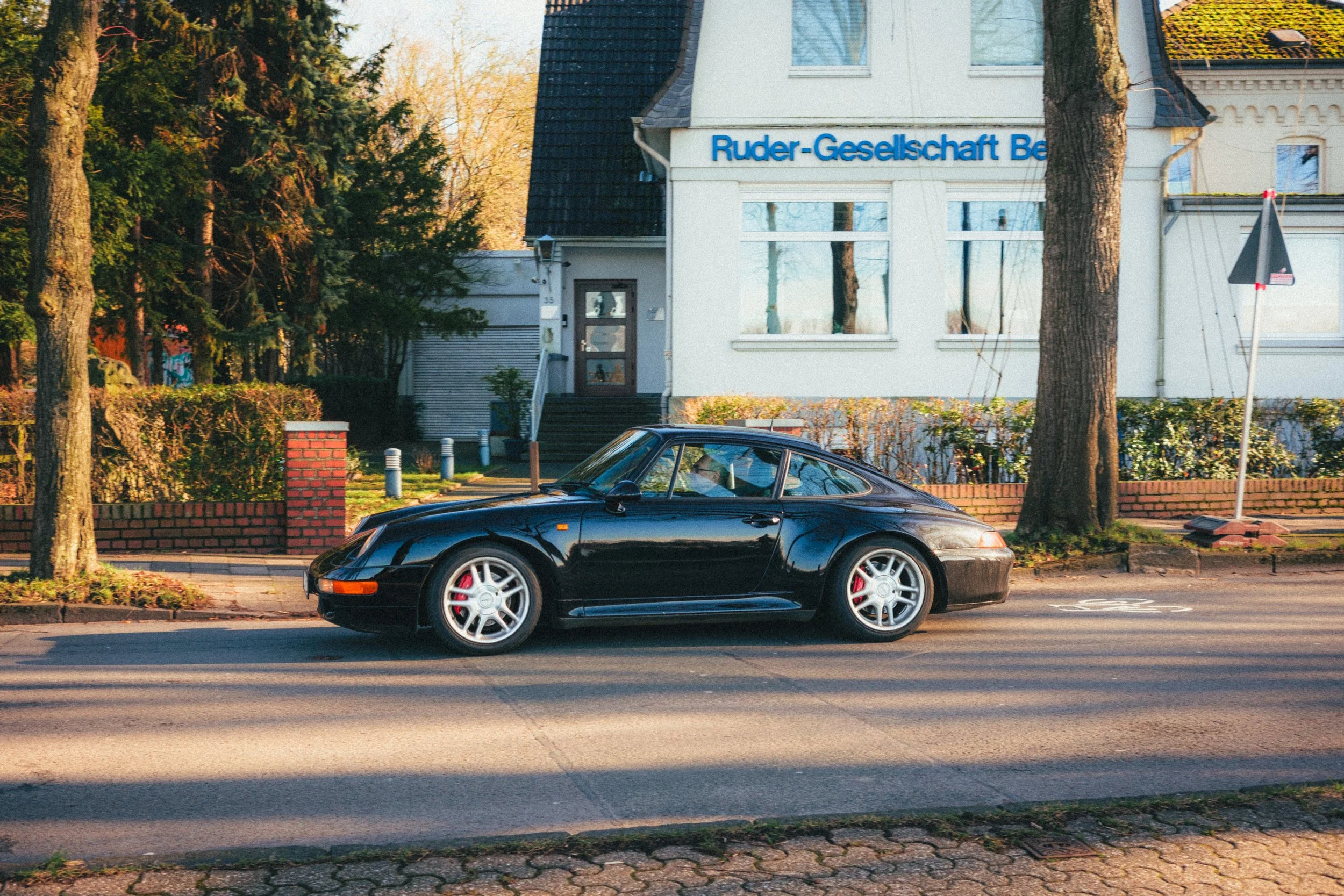 Vintage Porsche on a sunlit street in Düsseldorf, with classic German architecture and a serene urban backdrop. A fine art photograph capturing automotive elegance and city charm, ideal for collectors of premium urban photography.