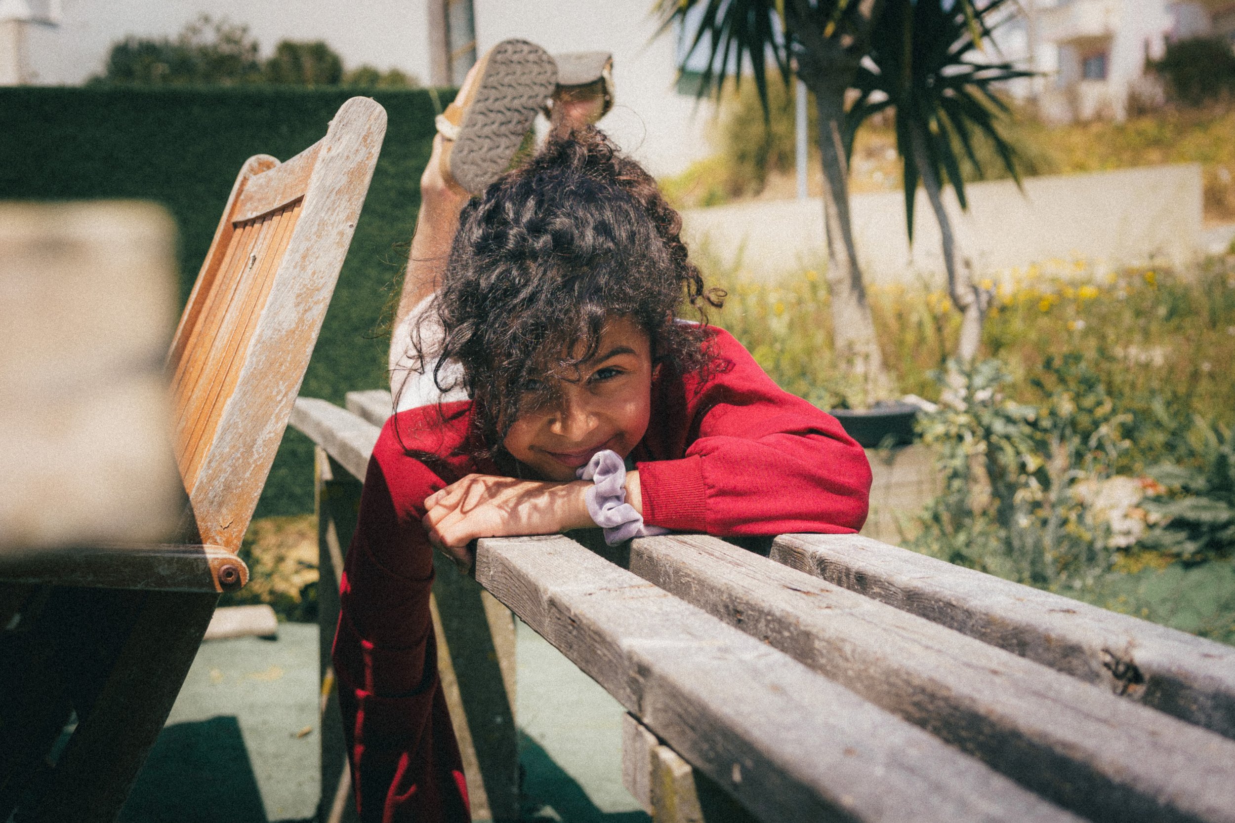 Portrait of Maria Alice Costa, relaxing at a bench and smiling at the camera.