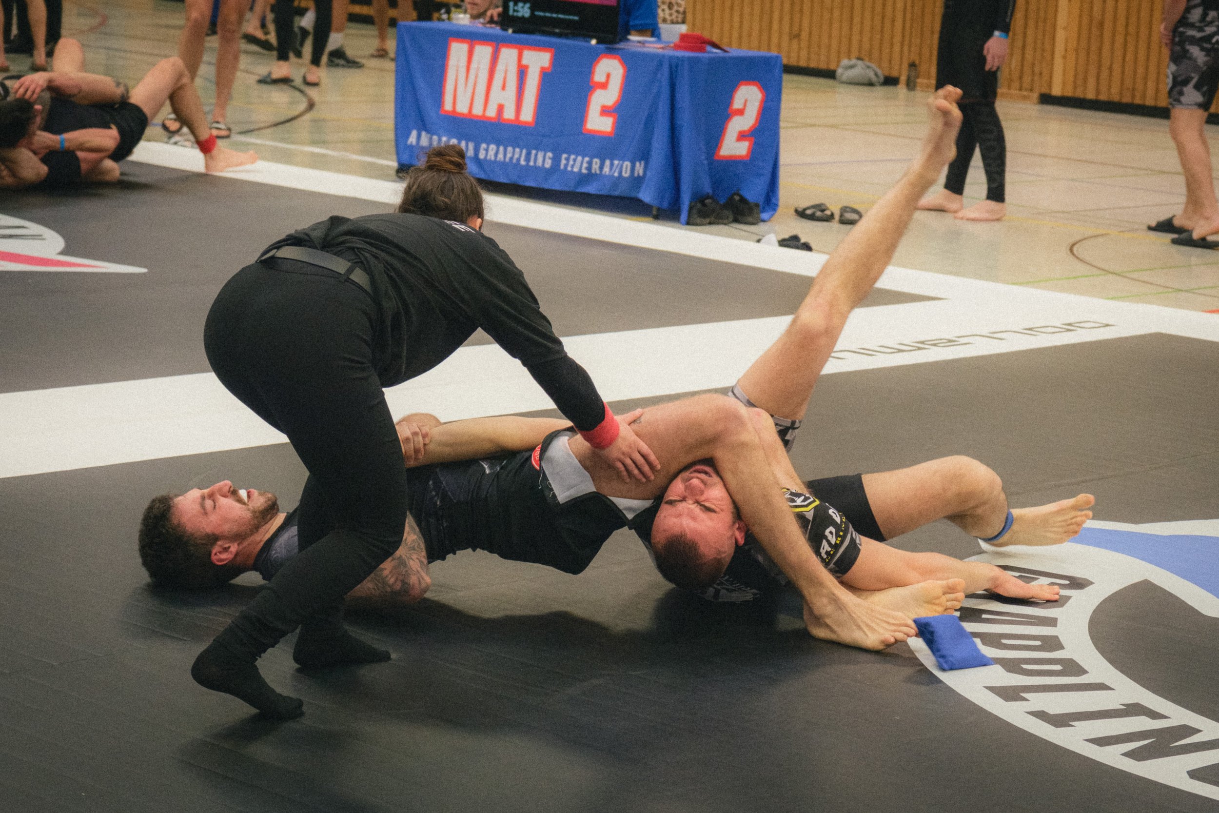 Portrait of BJJ athlete doing an harm lock during a fight in a Brazilian Jiu-jitsu event.