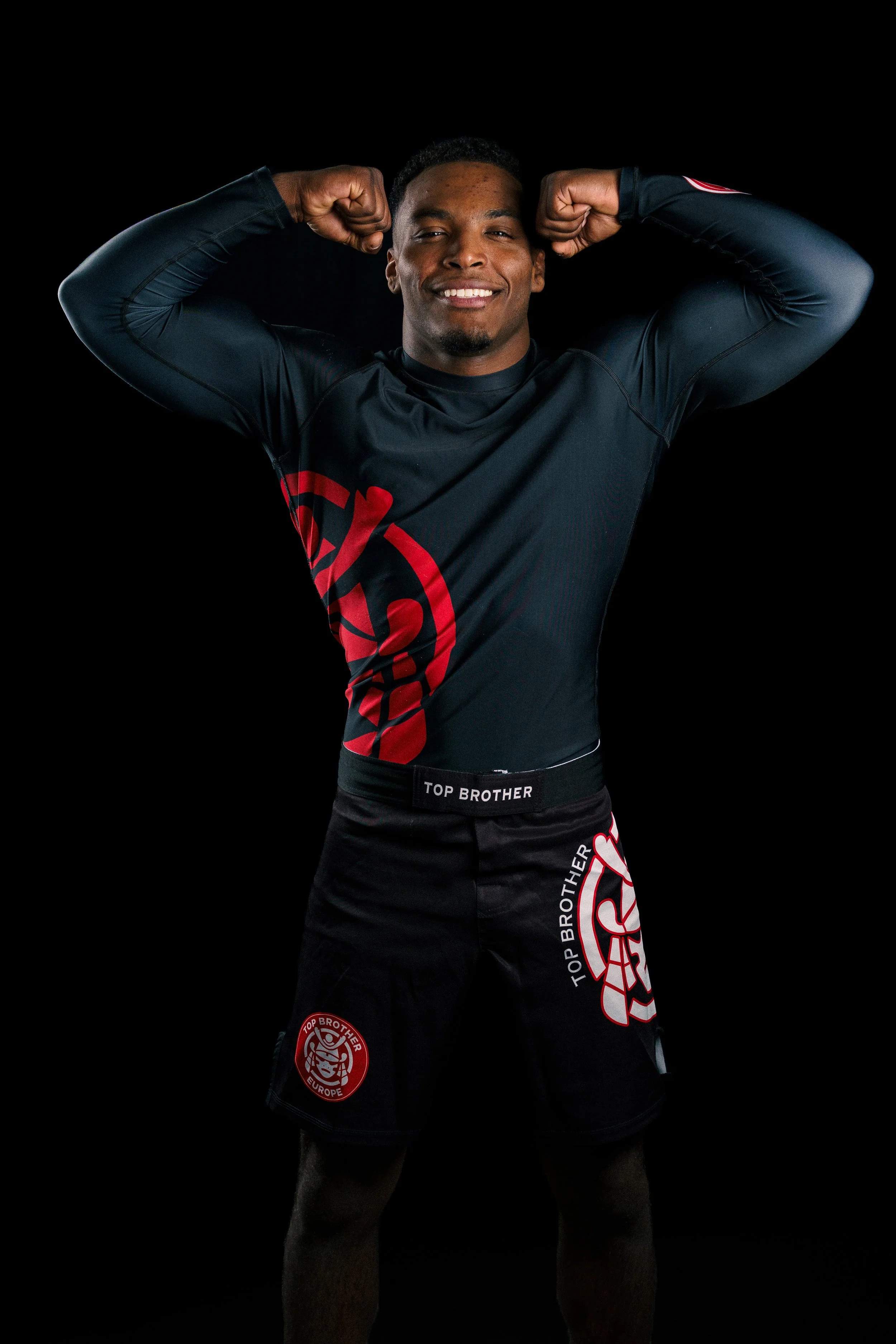 Studio portrait of a Brazilian Jiu-Jitsu athlete, Renan Malheiro from Top Brother, in nogi clothes, standing strong in a training hall.