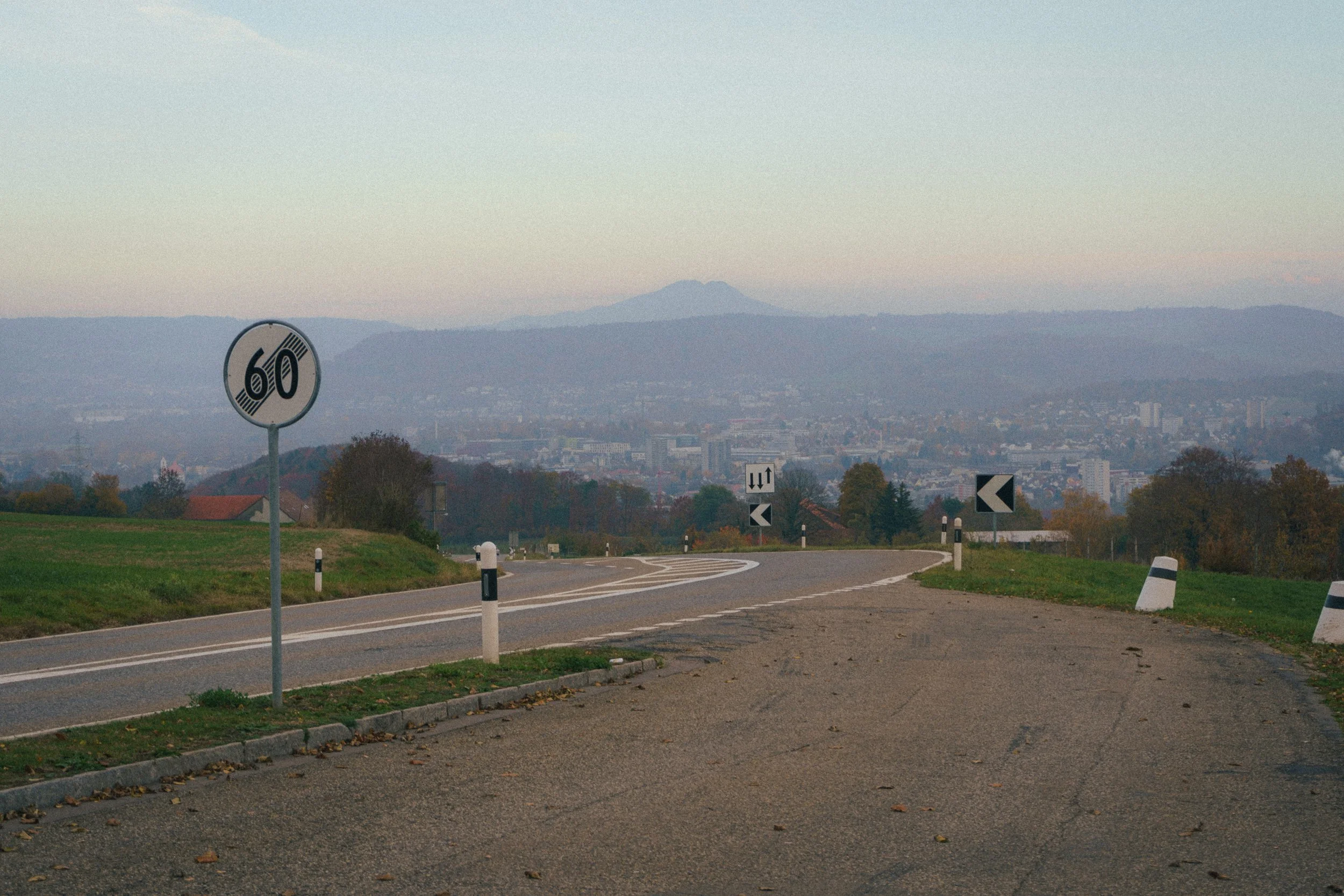 Fine art landscape of a read leading to the city of Zürich, Switzerland and a road sign on the left.