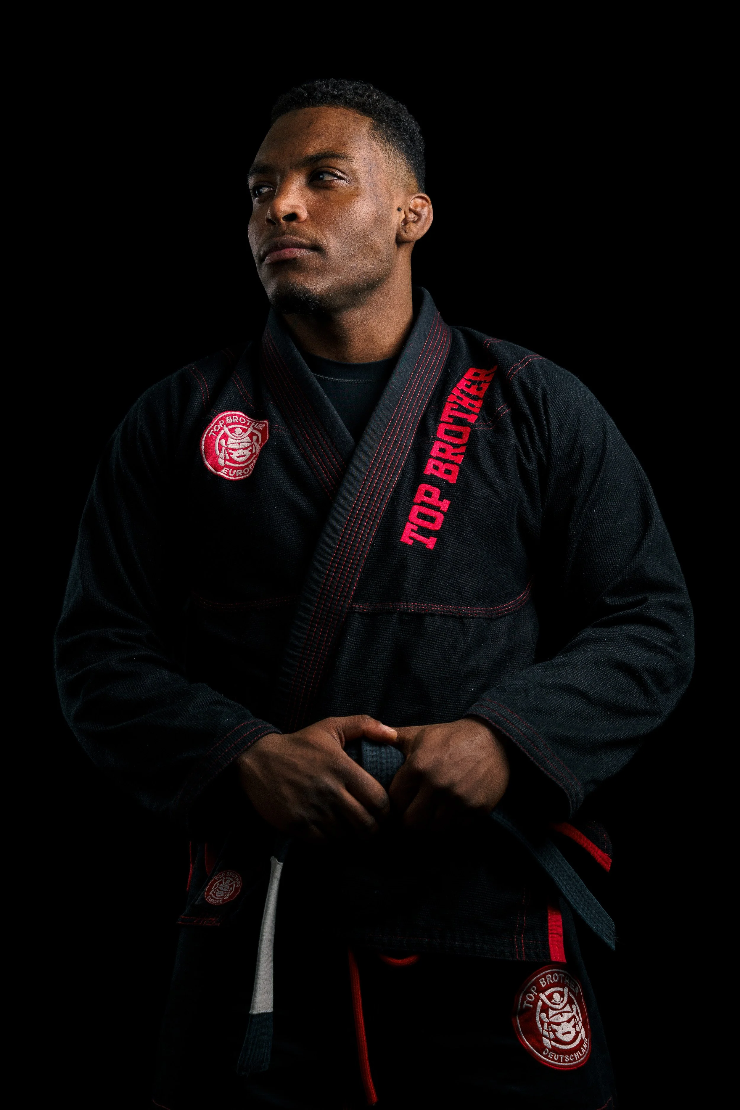 Studio portrait of a BJJ athlete, Renan Malheiro, wearing a black go, gazing at the side.