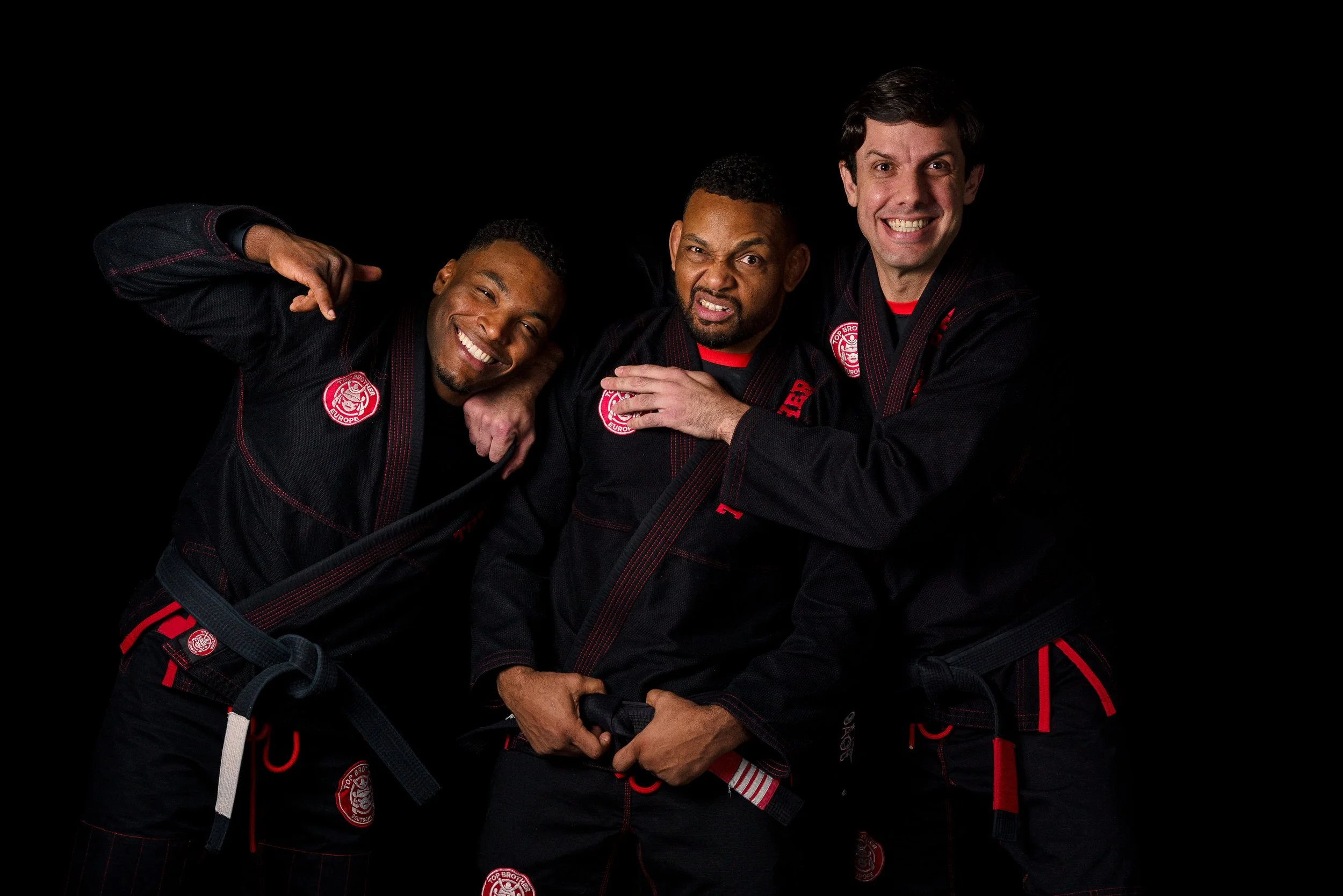 Studio portrait of the tree teachers from Top Brother Düsseldorf, Alex Malheiro, Renan Malheiro e João Macedo, wearing black gis, looking playful.