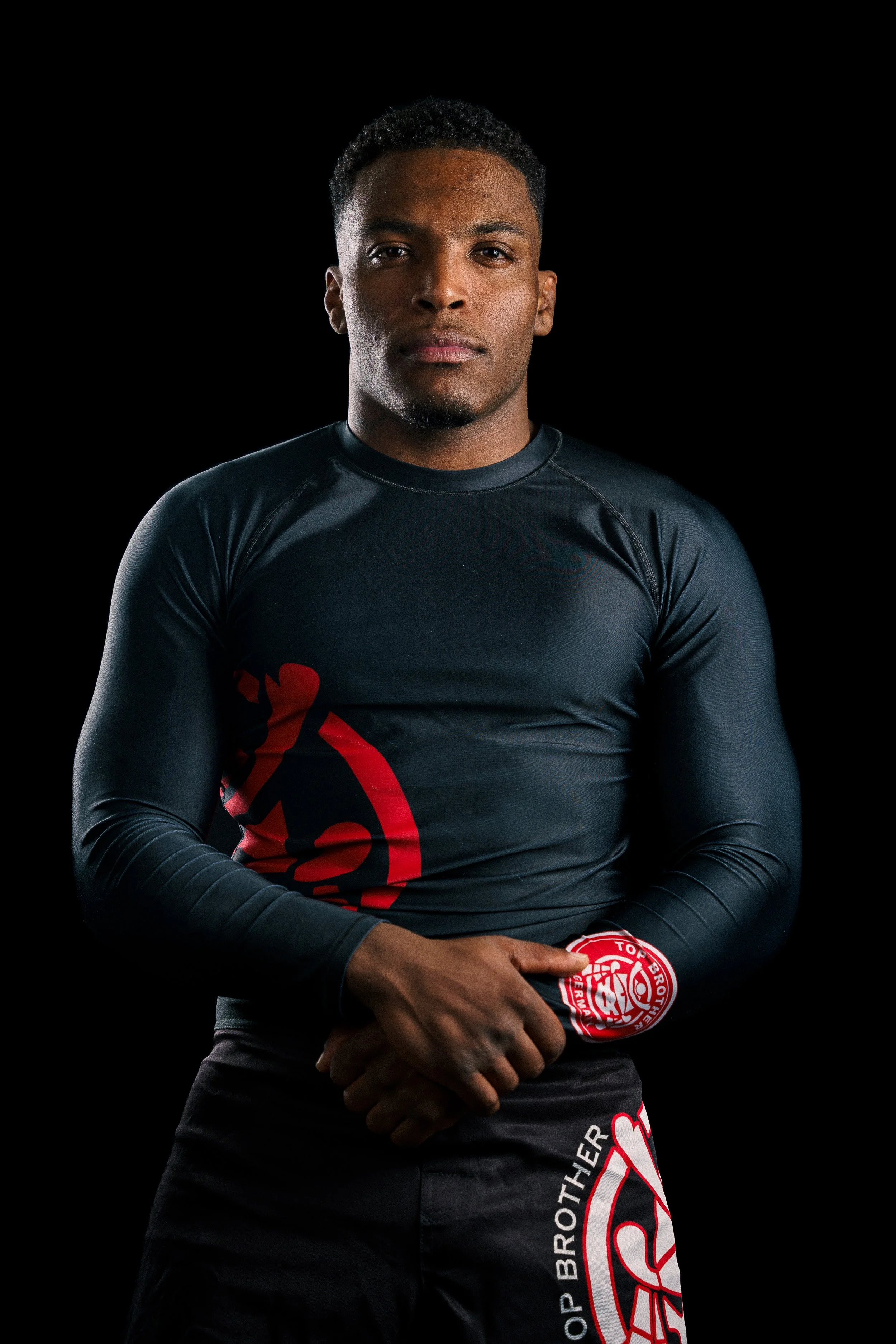 Studio portrait of a Brazilian Jiu-Jitsu athlete, Renan Malheiro from Top Brother, in nogi clothes, standing confidently in a training hall.